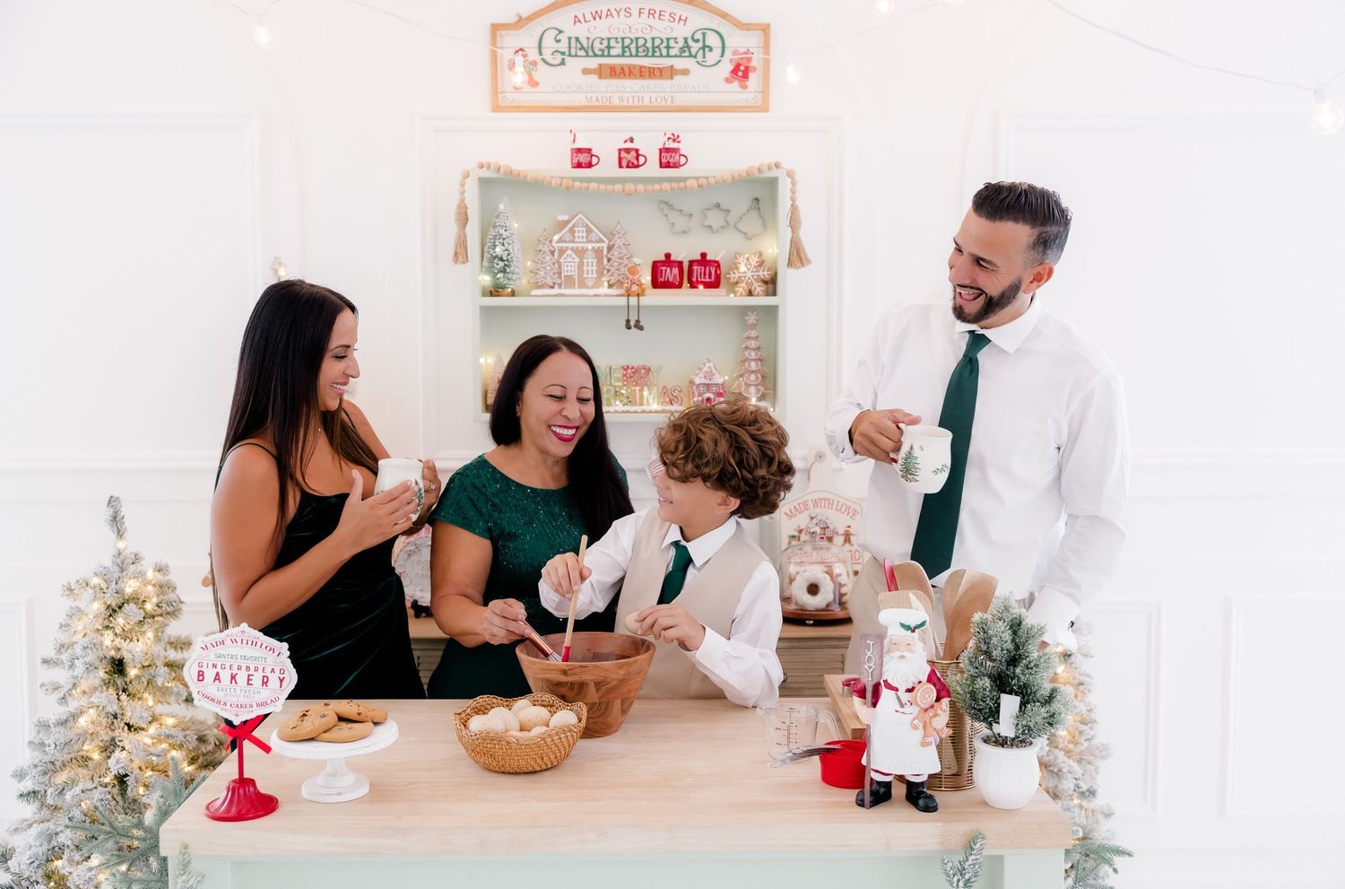 Family of four laughing together at a festive gingerbread decorating station with holiday decor.