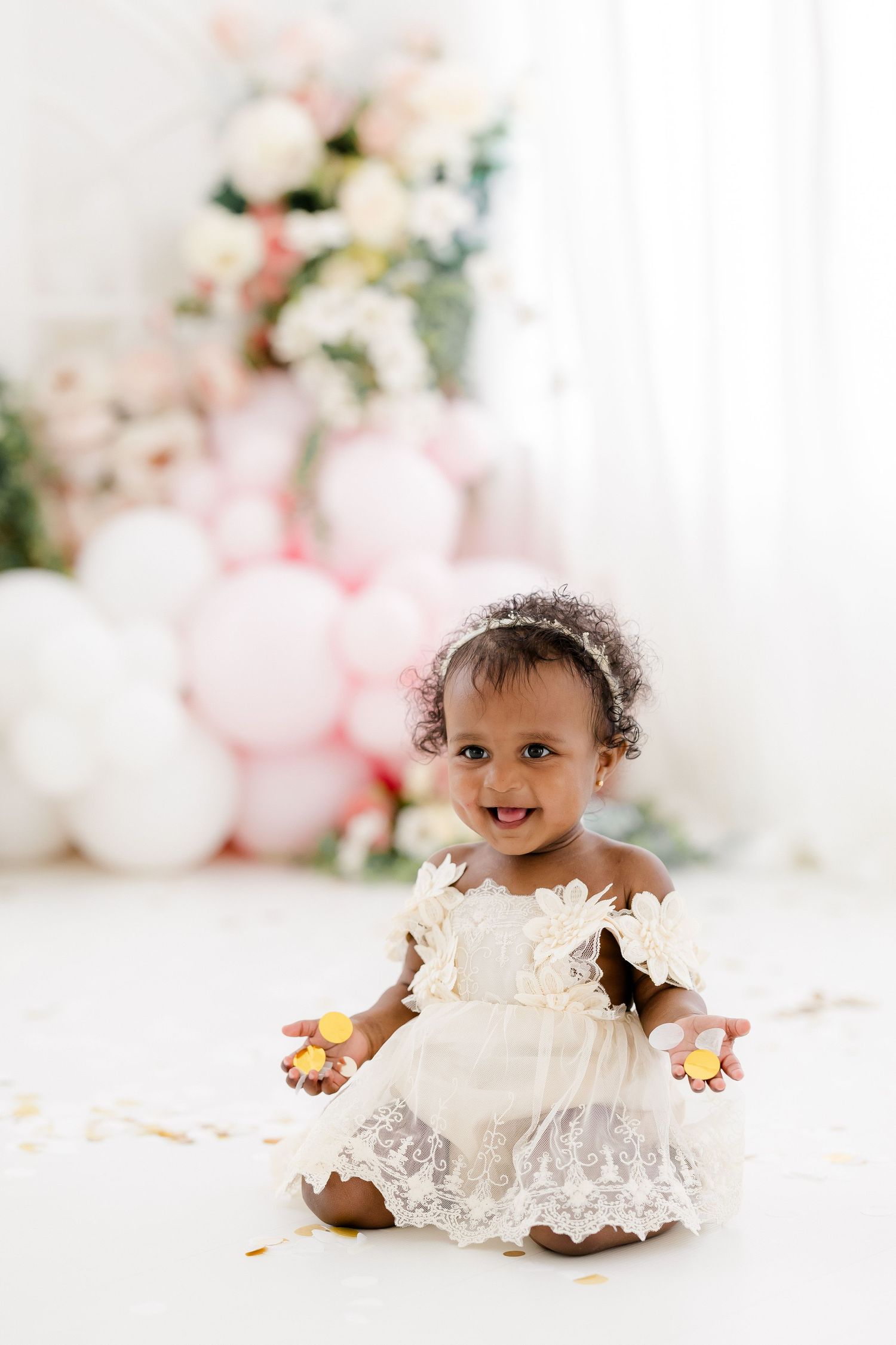 Sweet first birthday photo setup with lace dress and pink floral decorations.
