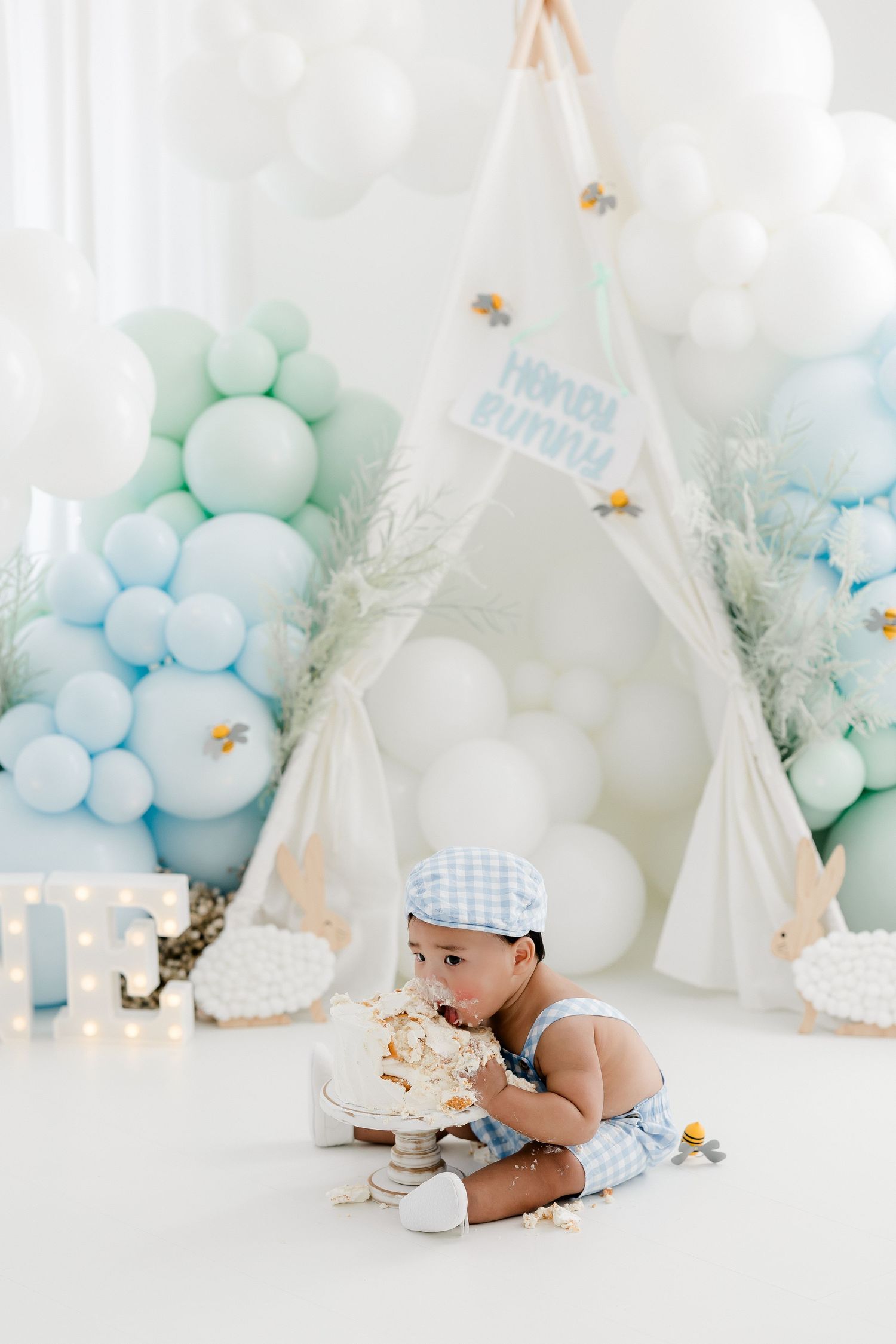 Elegant first birthday setup with white teepee and mint green balloon garland.