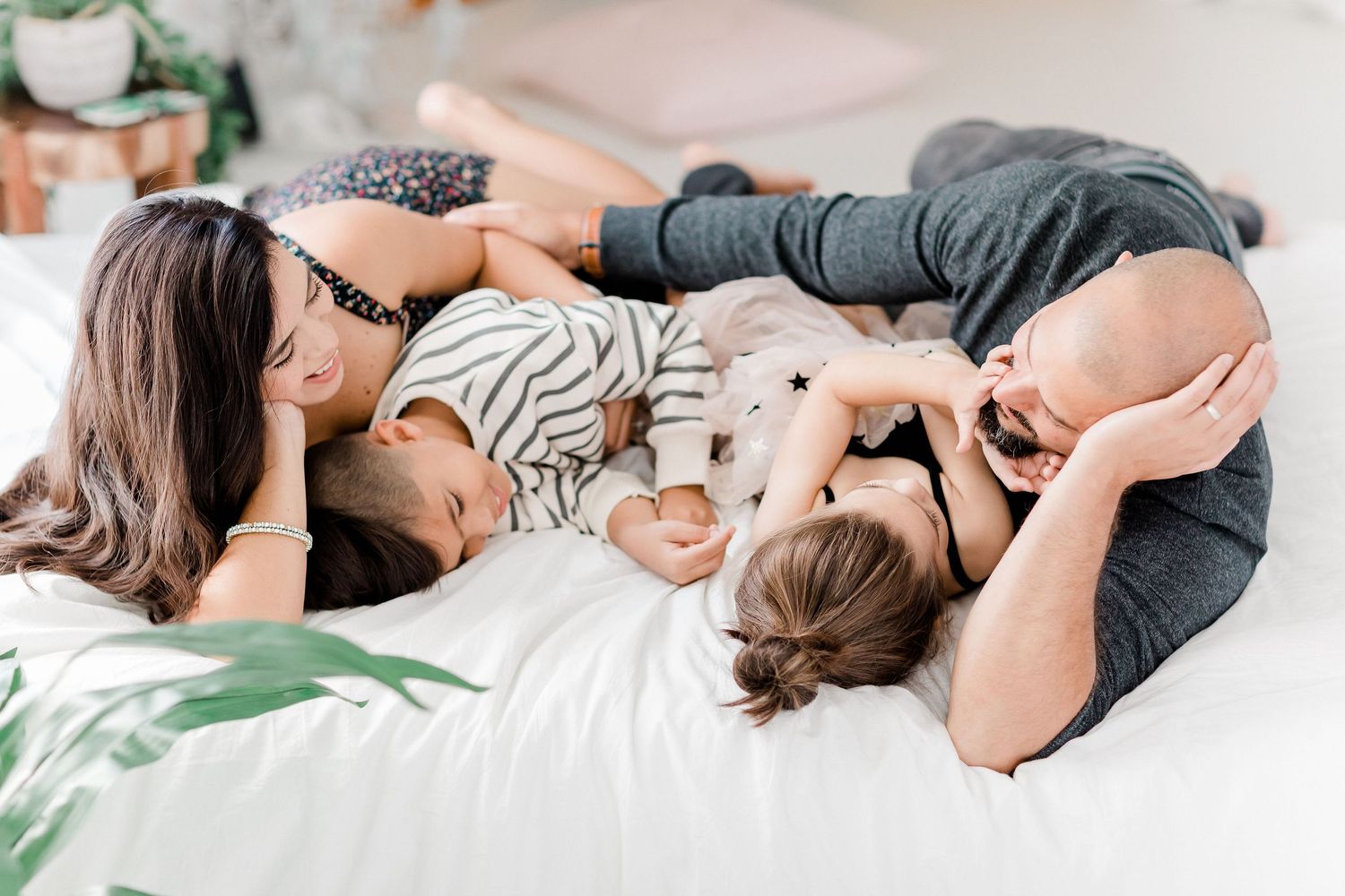 A series of intimate lifestyle photos showing tender moments between parents and children on white bedding.