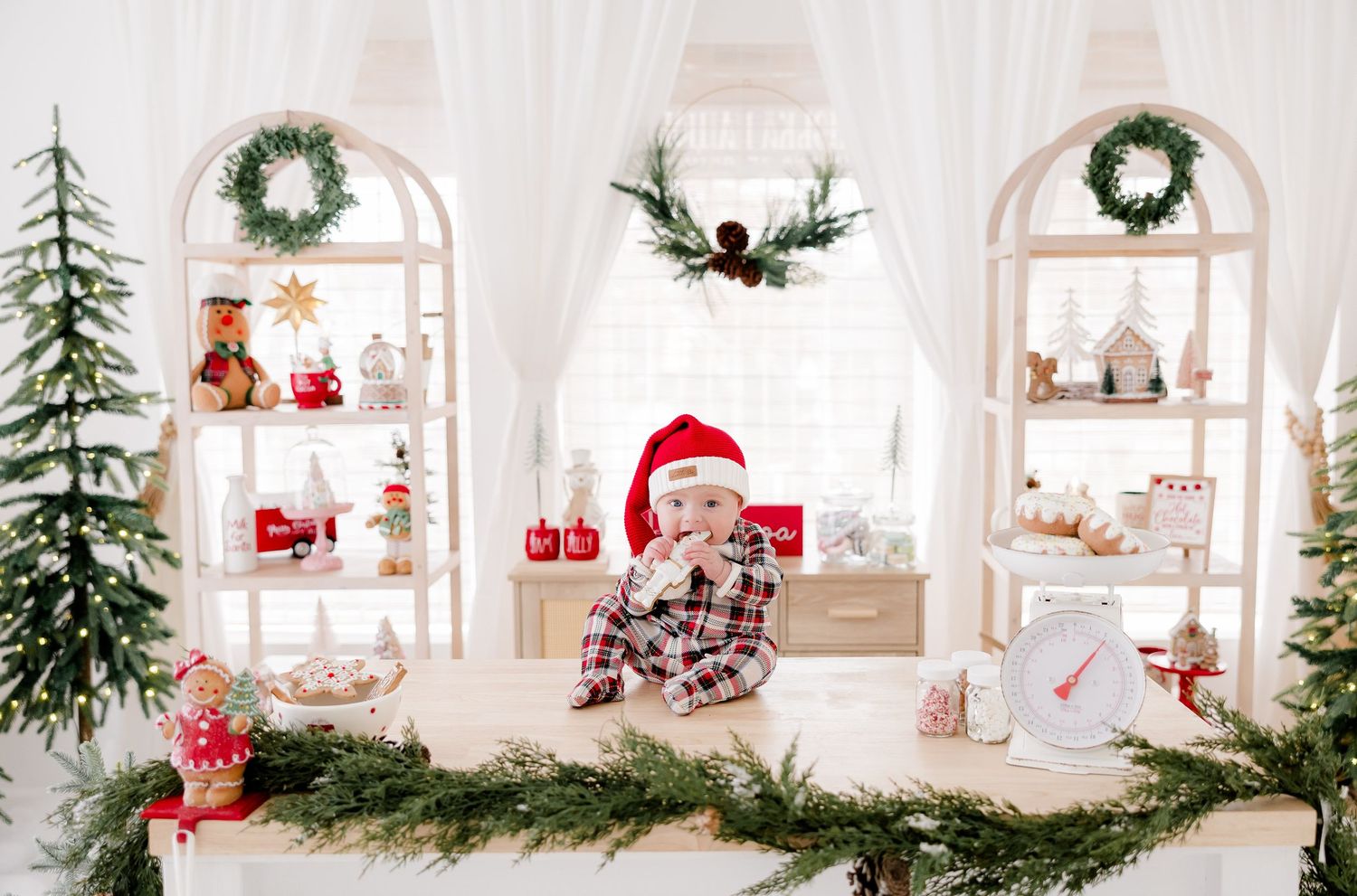 White Christmas studio with arched windows, wreaths, and holiday decorations.