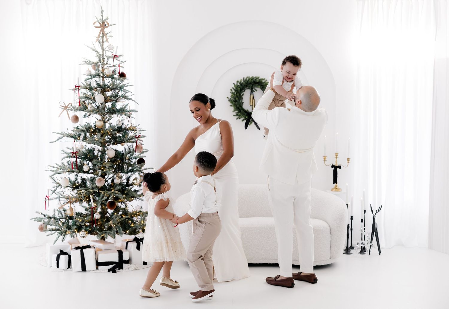 Sweet family moment captured in white studio with decorated Christmas tree.nj holiday mini sessions