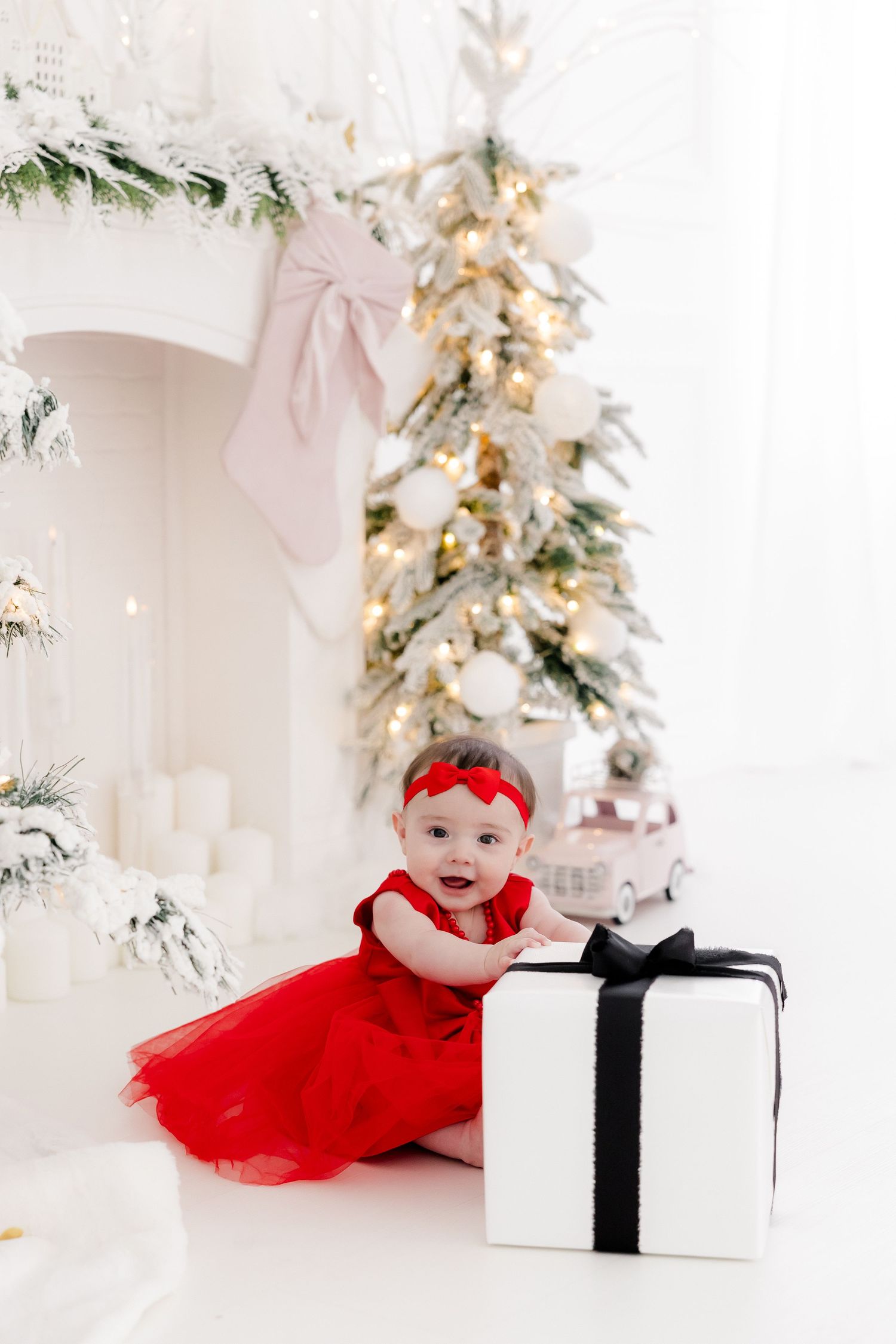 Holiday portrait setup with red tulle dress, white wrapped presents and sparkly Christmas tree.