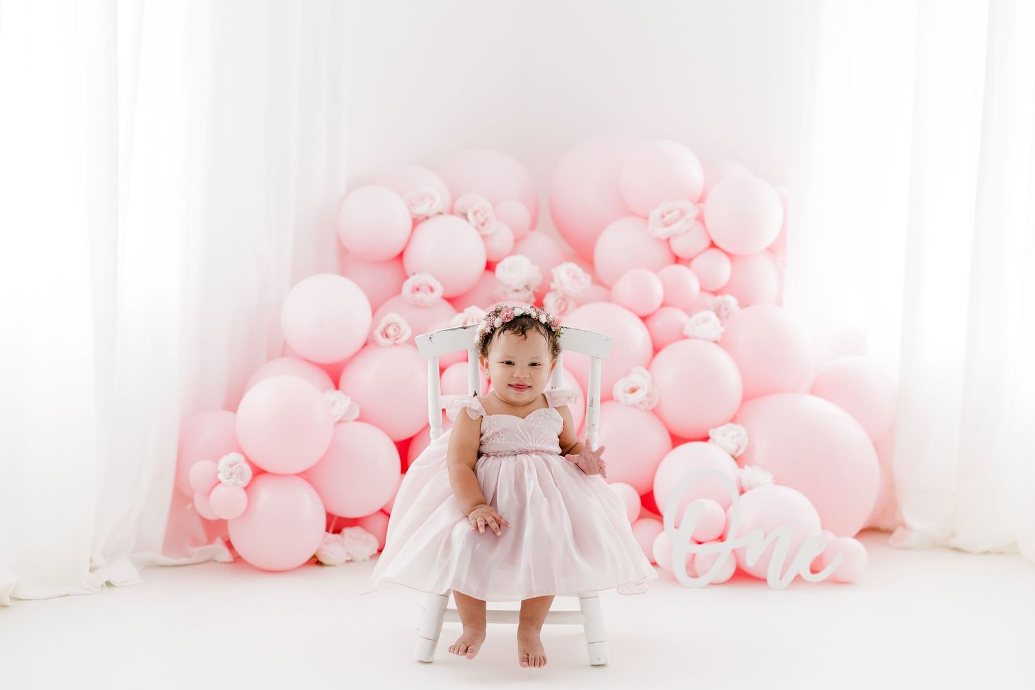 Sweet celebration setup with pink balloons and white backdrop.