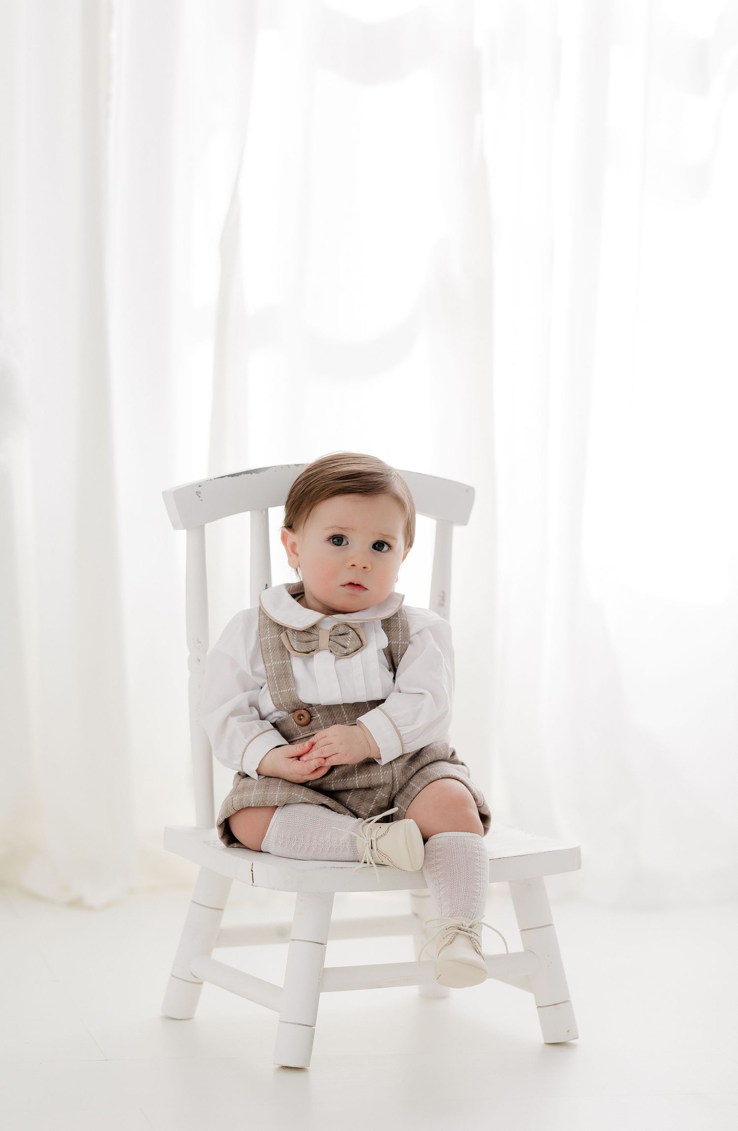 Classic portrait setup with white wooden chair against soft white backdrop.