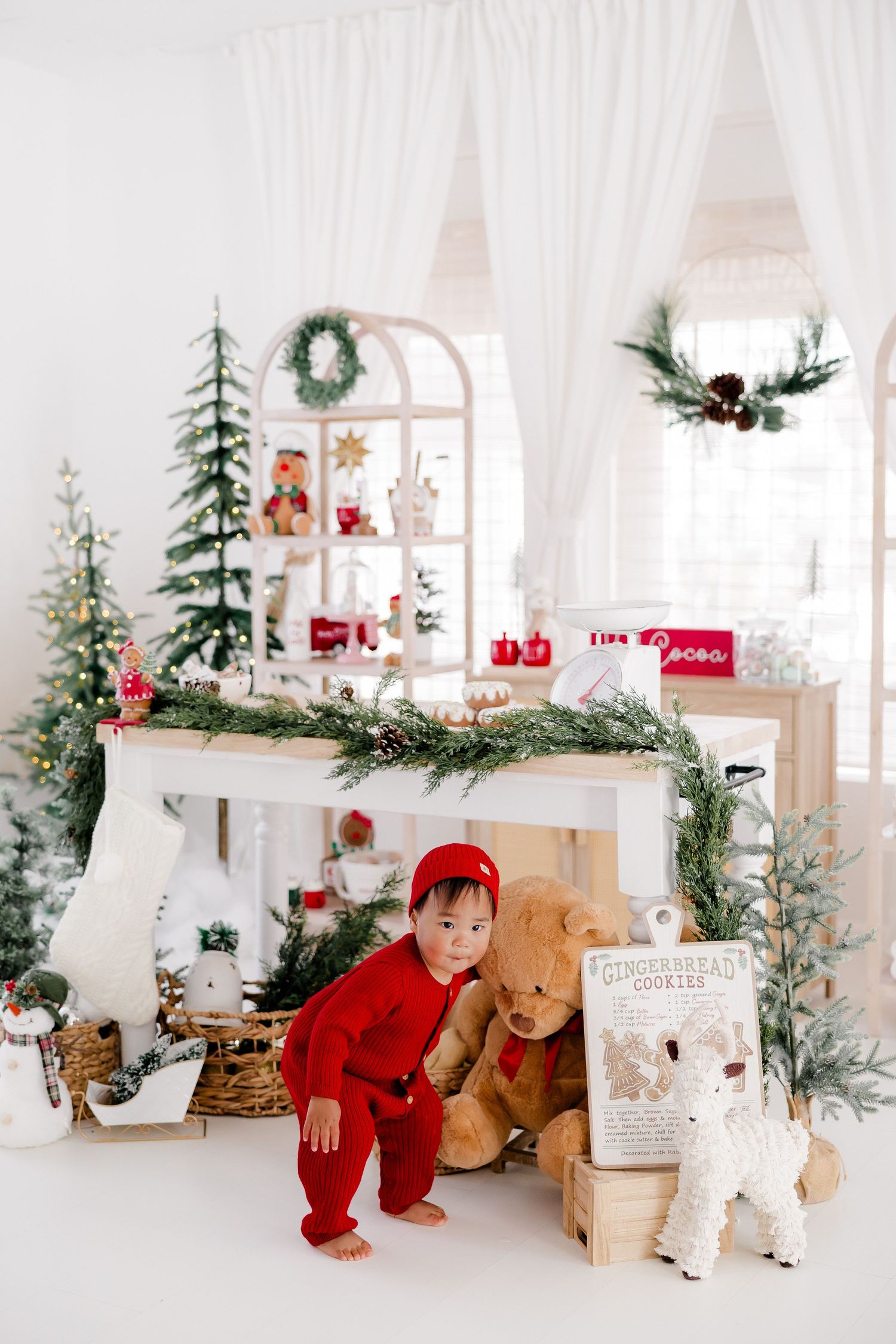 Holiday-themed white studio with wooden toys, Christmas trees, and festive decorations.