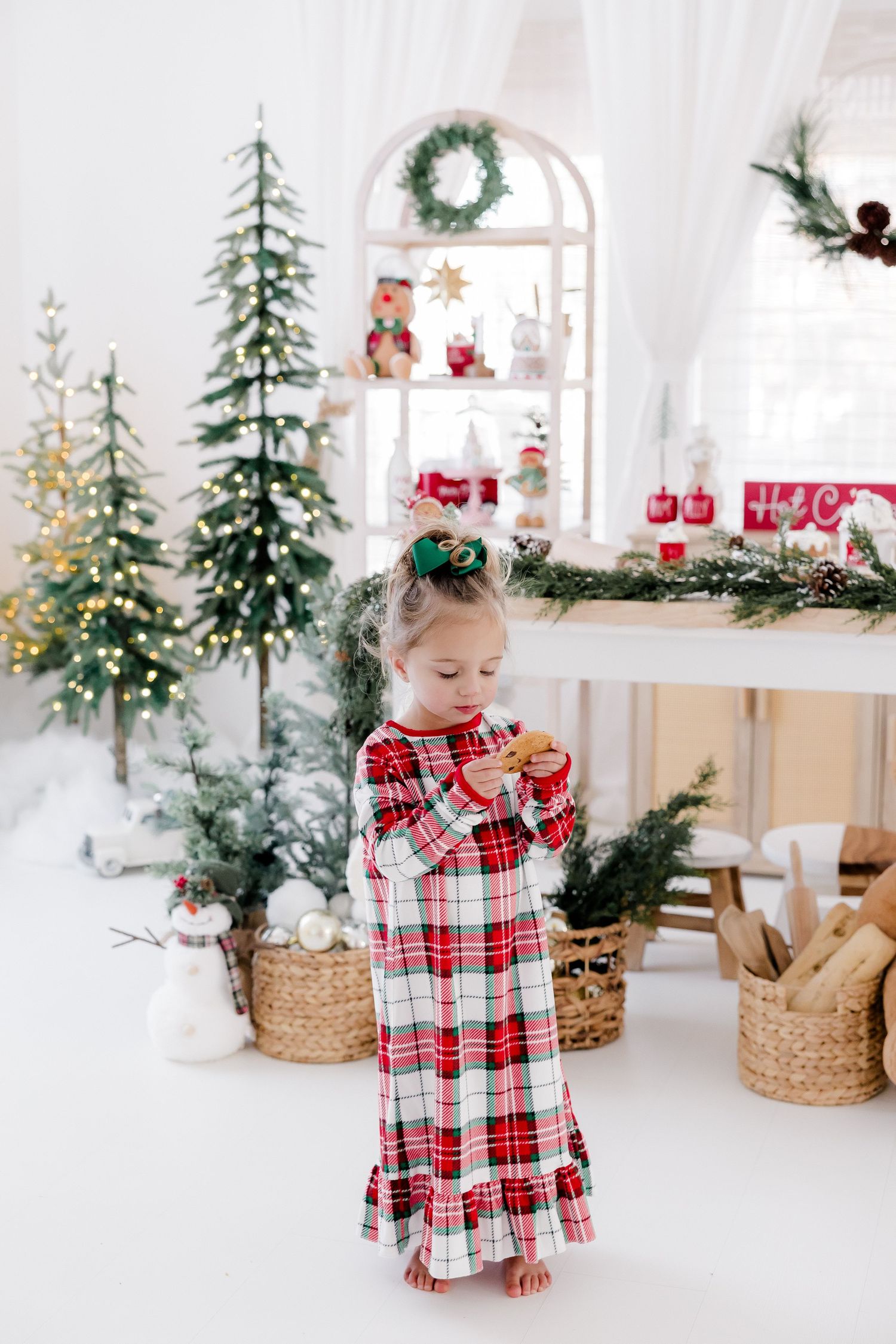 Small child in plaid holiday outfit exploring festive Christmas decor display.