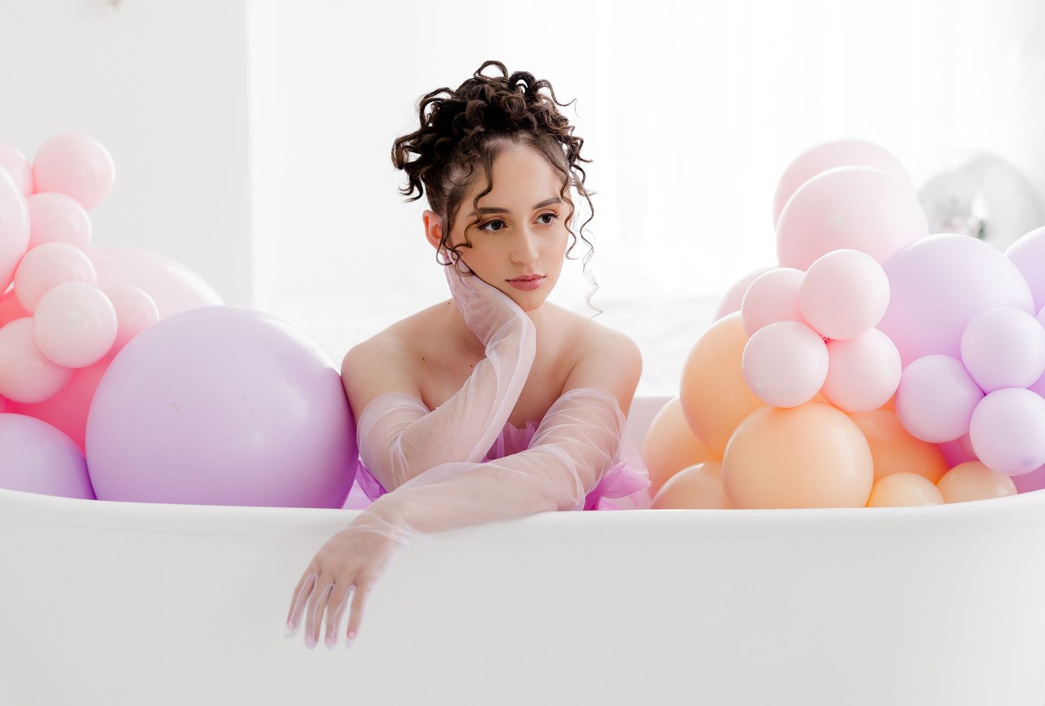Ethereal bridal portrait with soft pastel balloons and delicate tulle creating a dreamy, romantic atmosphere.