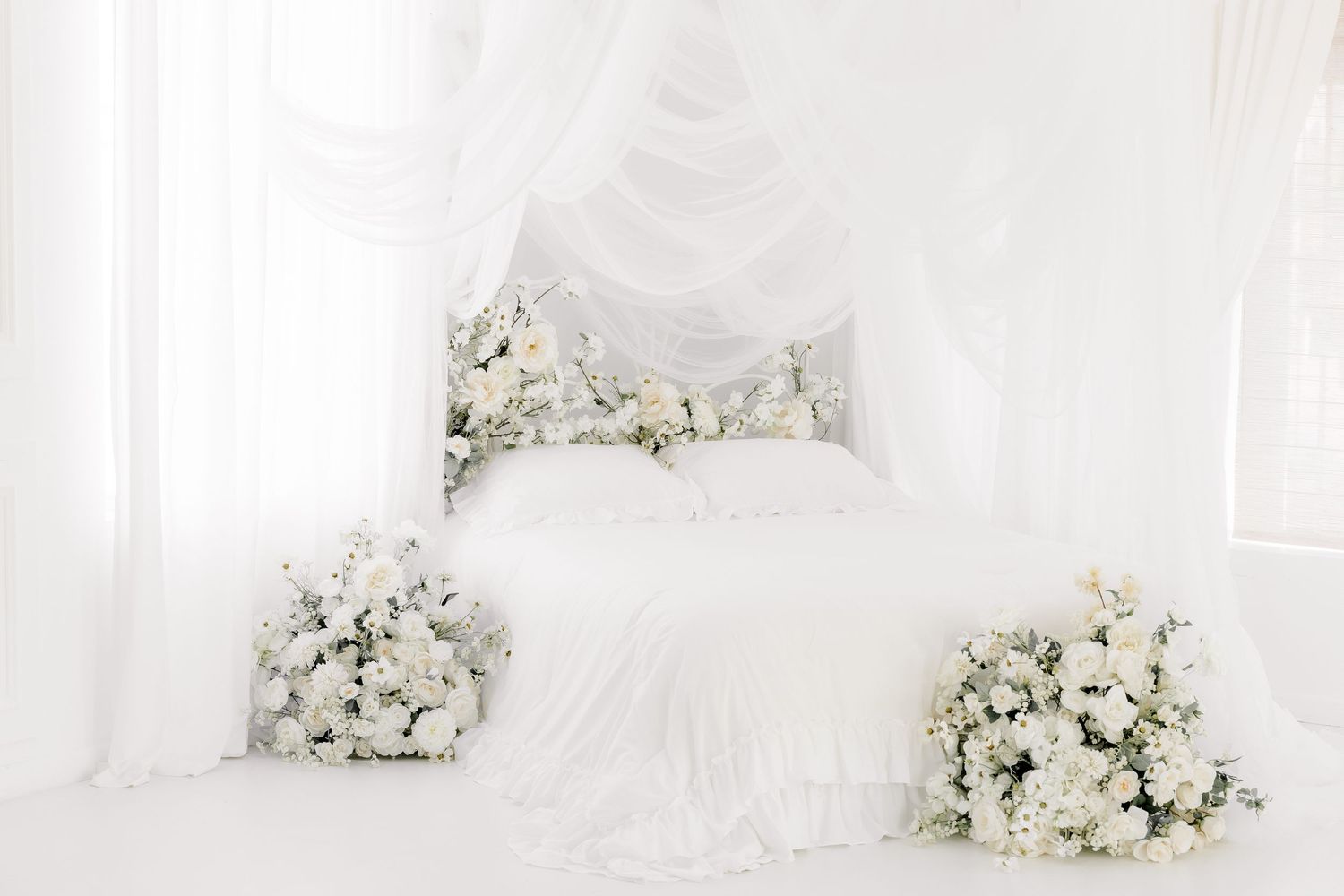 A white and cream colored wedding dress hangs elegantly against a light backdrop with floral arrangements.