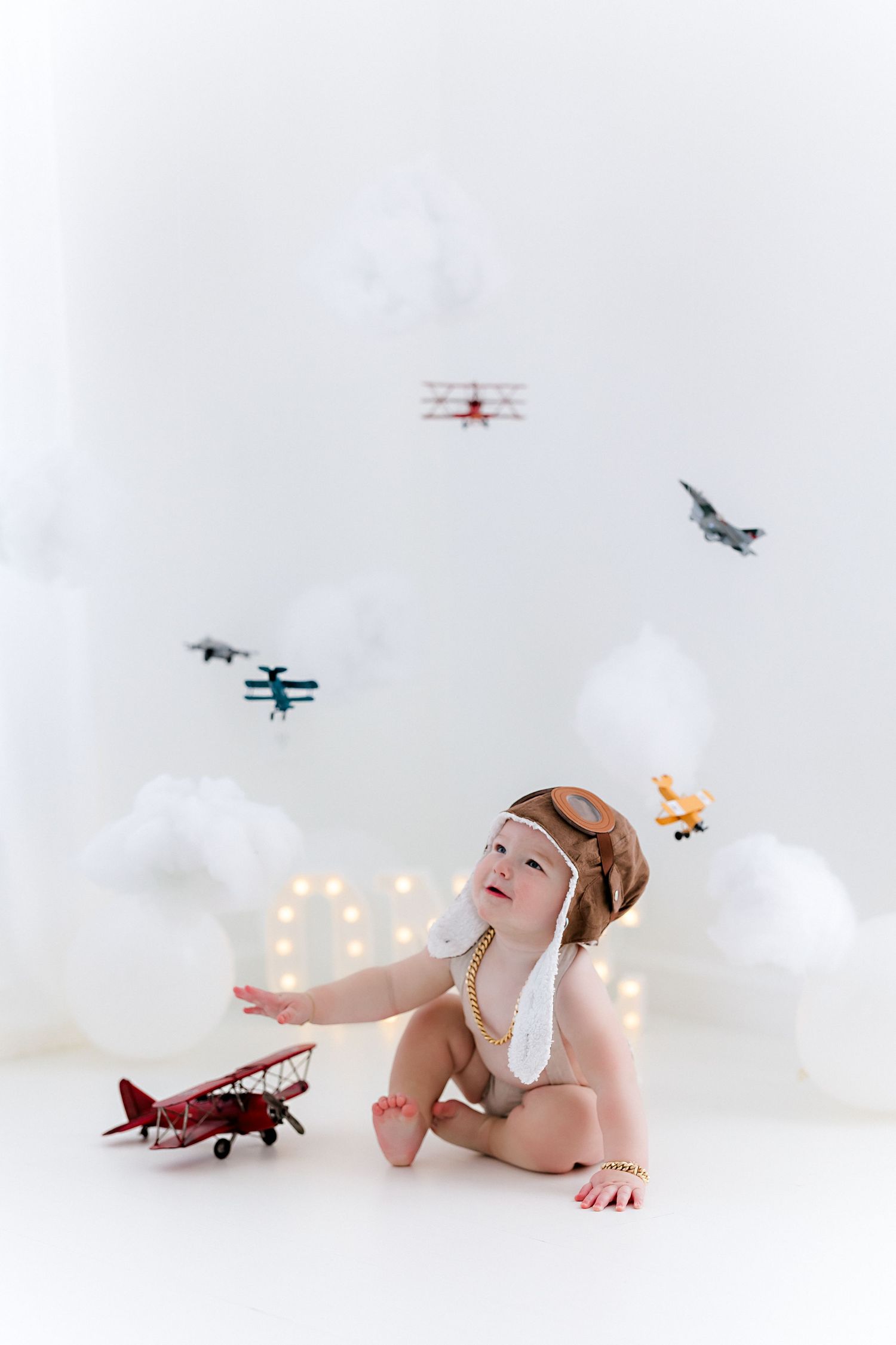 Vintage toy airplanes fly across a dreamy white backdrop with soft bokeh lights creating a whimsical scene.