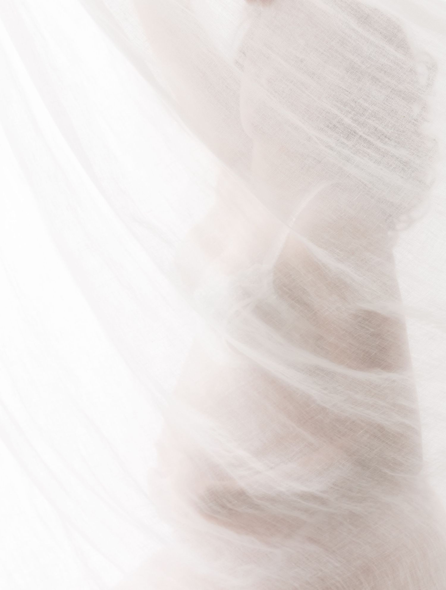 Abstract white and beige flowing fabric texture with soft ethereal movement and delicate folds.