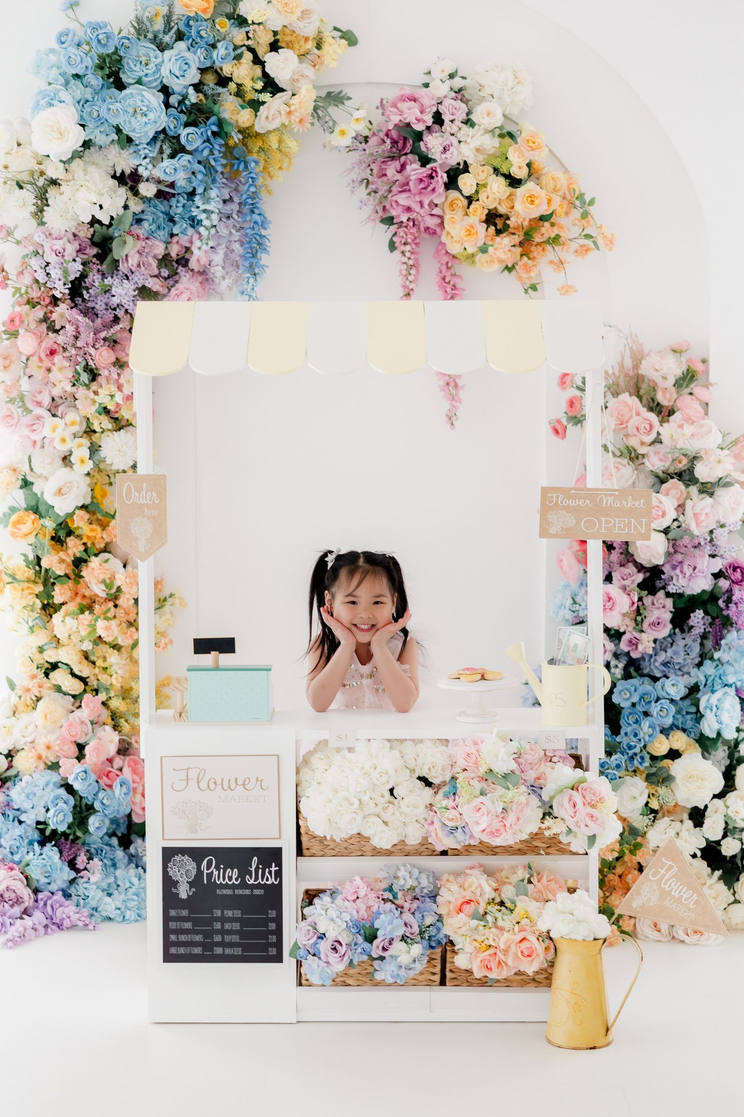 Floral photography backdrop with pastel pink and blue flowers arranged in an arch with chalkboard menu signs.