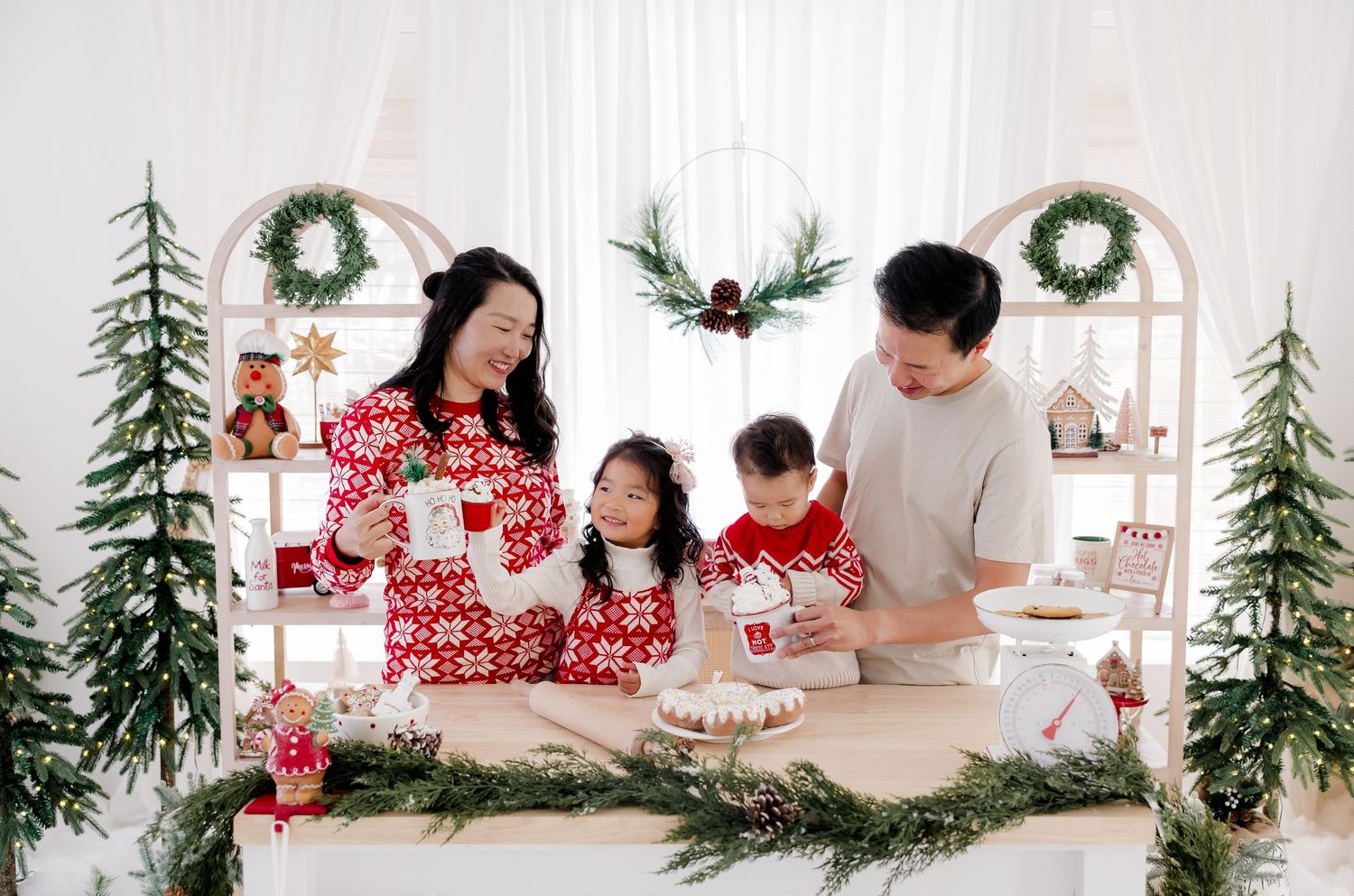 Family gathering around Christmas decorations in coordinated holiday outfits.