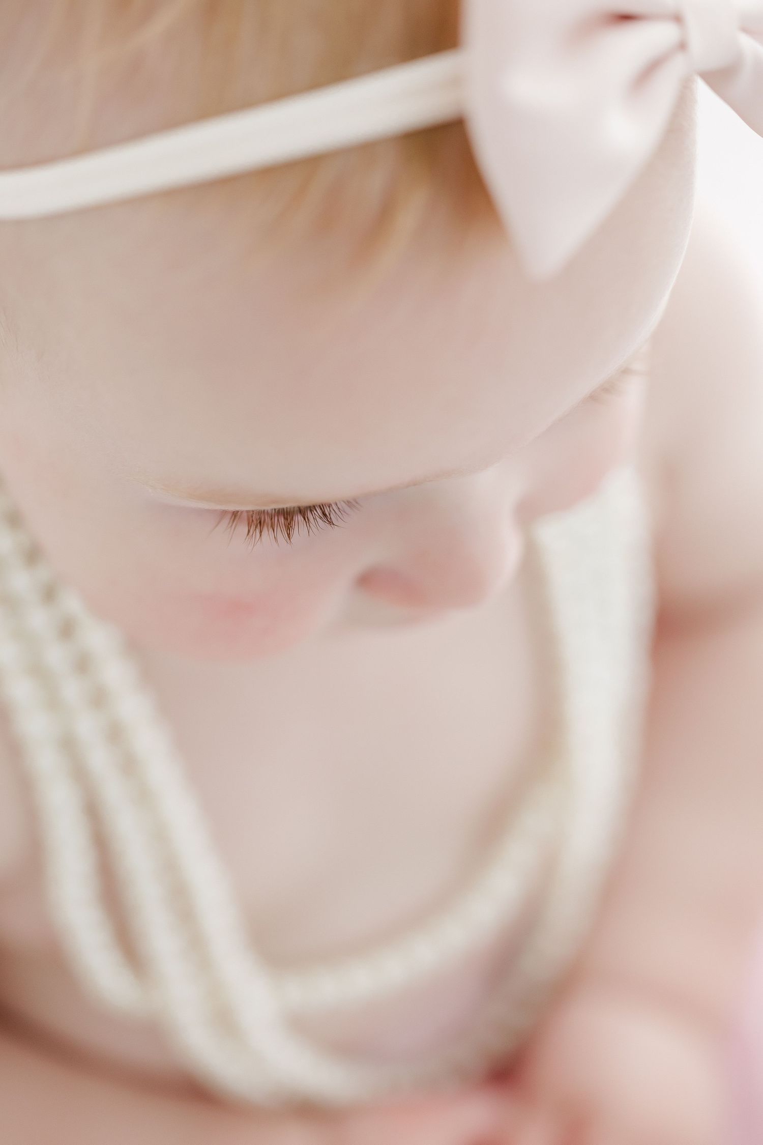 Close-up macro photography of a sleeping baby's delicate features in soft pink tones.