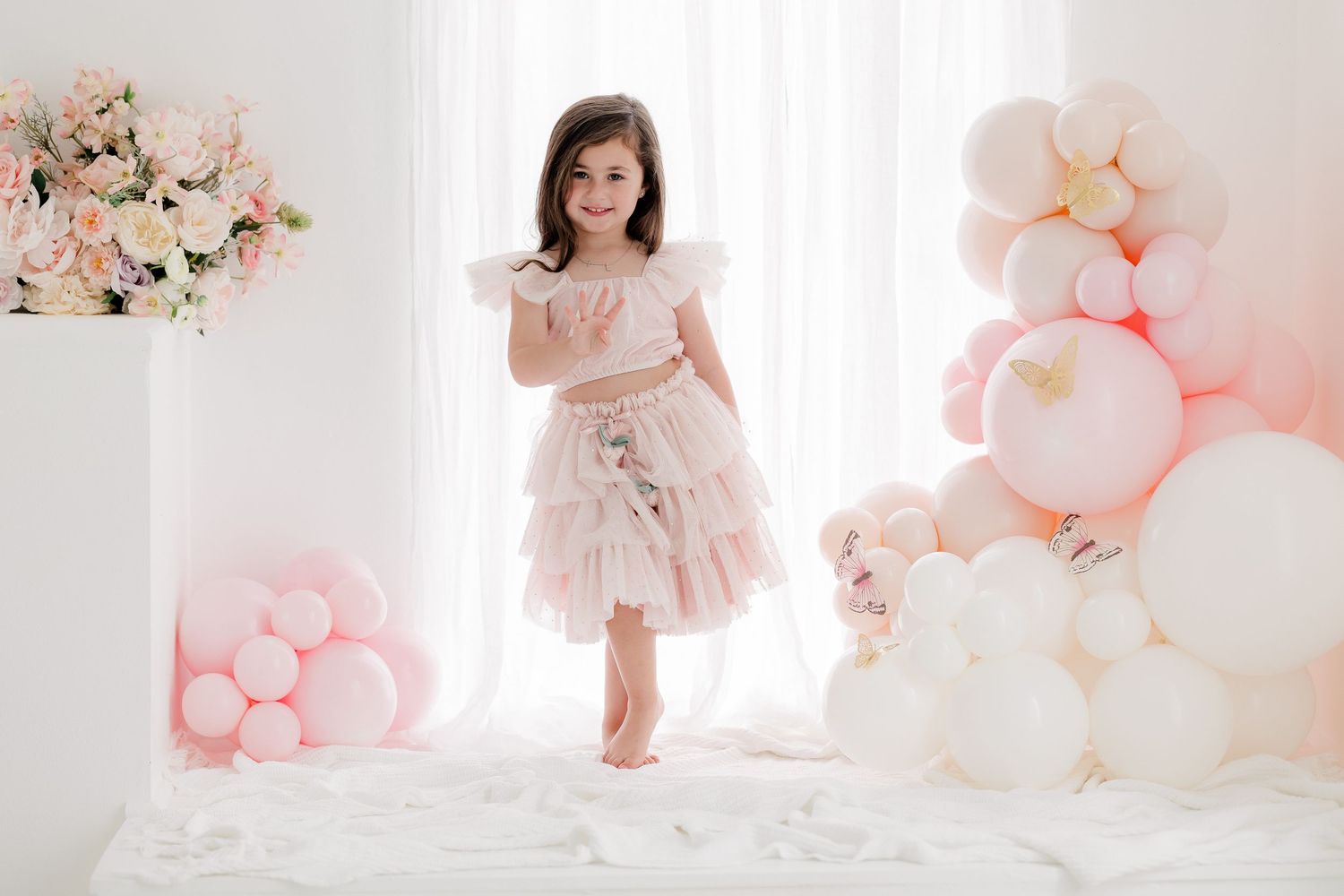 A dreamy portrait session with soft pink and white balloons and floral decorations creating a romantic atmosphere.
