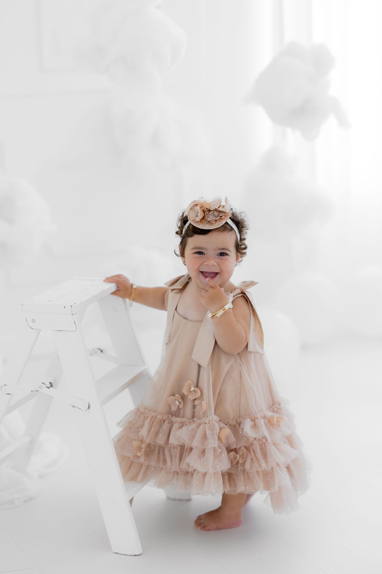 Whimsical portrait session with beige tulle dress and white backdrop.