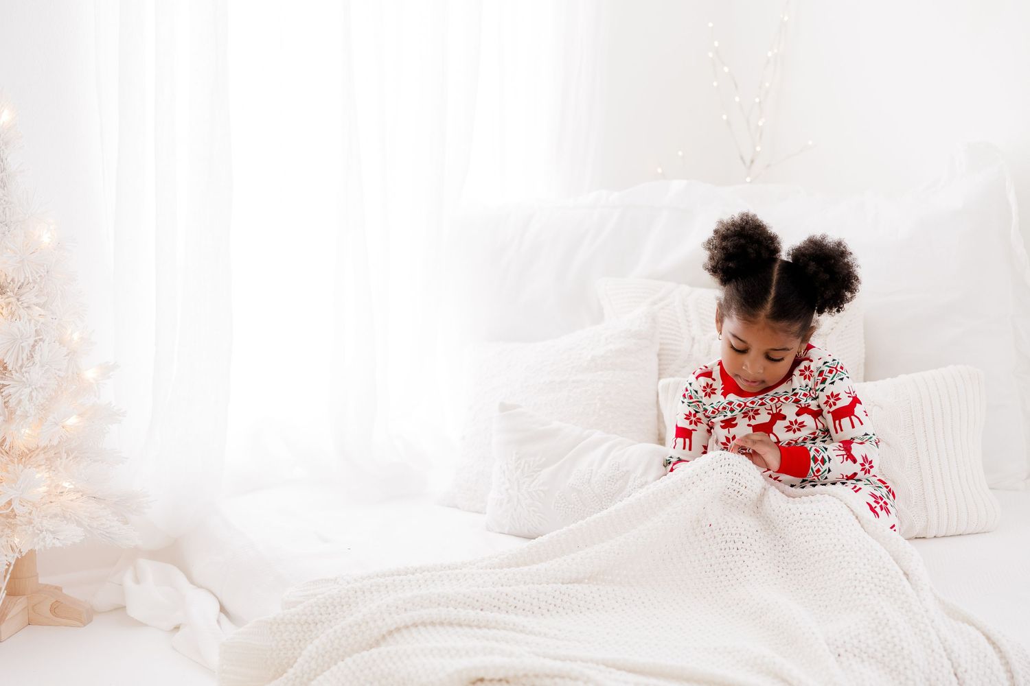 Cozy bed scene with white linens and holiday decorations.
