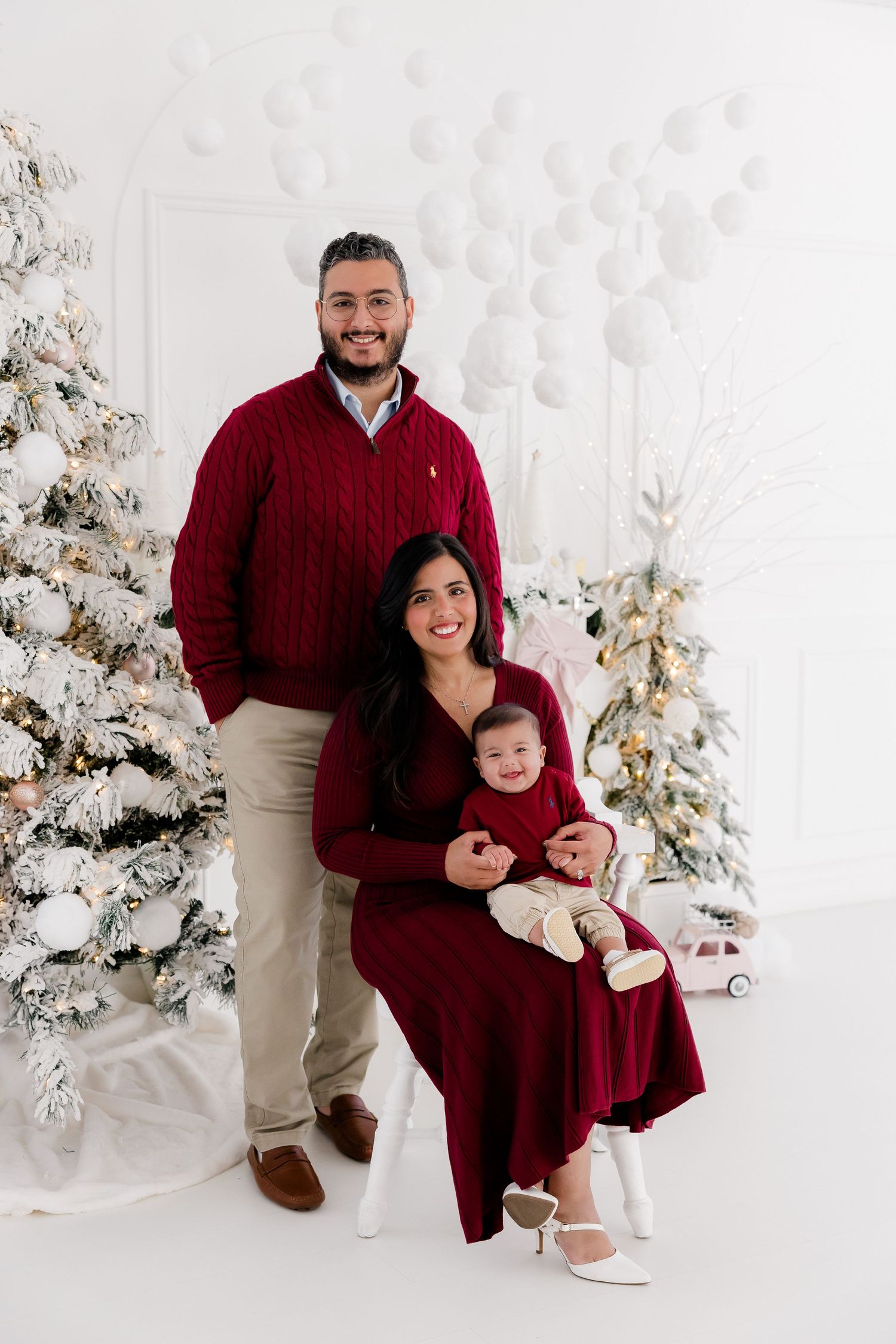 Family wearing coordinated burgundy outfits poses together for holiday portraits.
