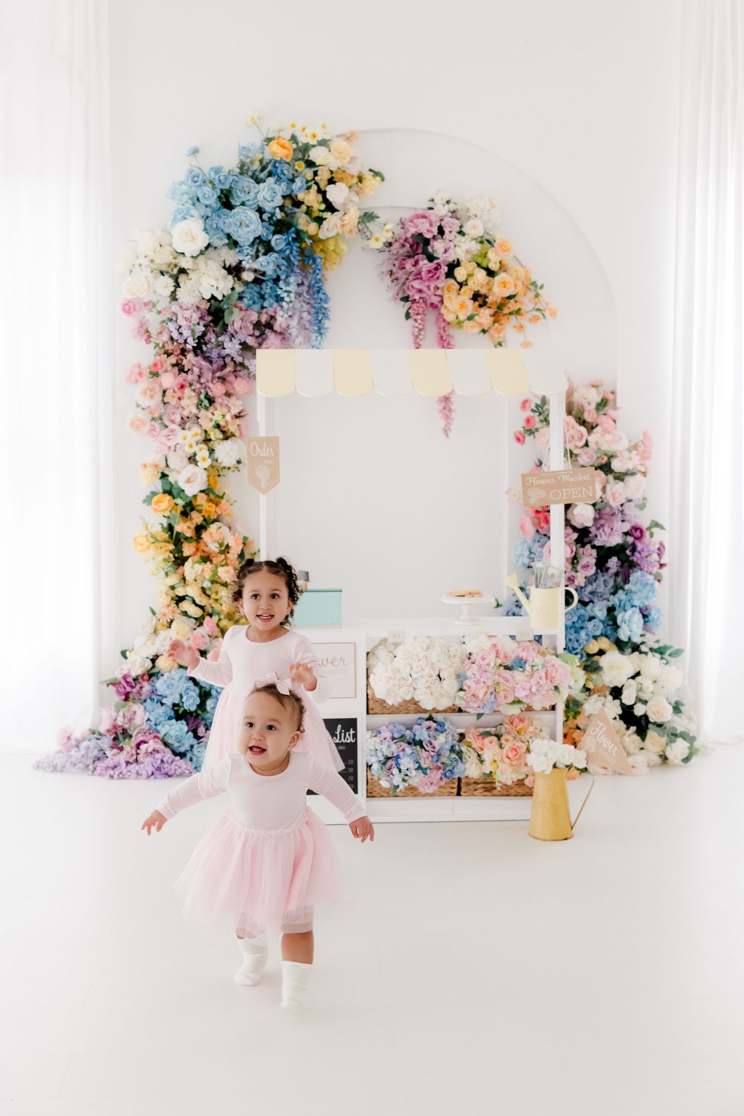 Colorful floral arch installation with pastel flowers creates a dreamy backdrop for a photography session.