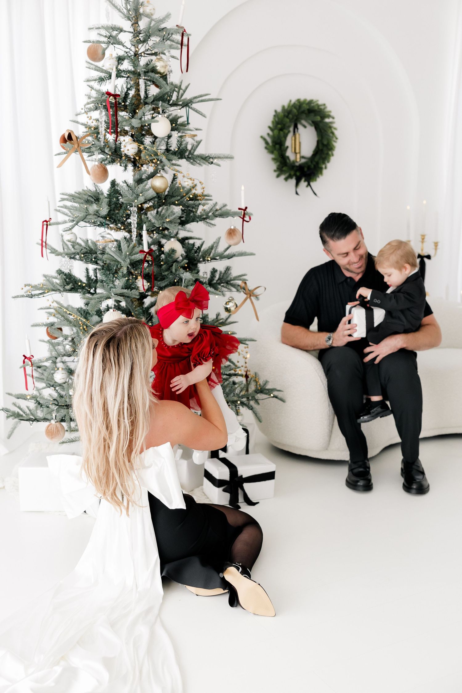 Holiday family photo session with Christmas tree and white studio backdrop.