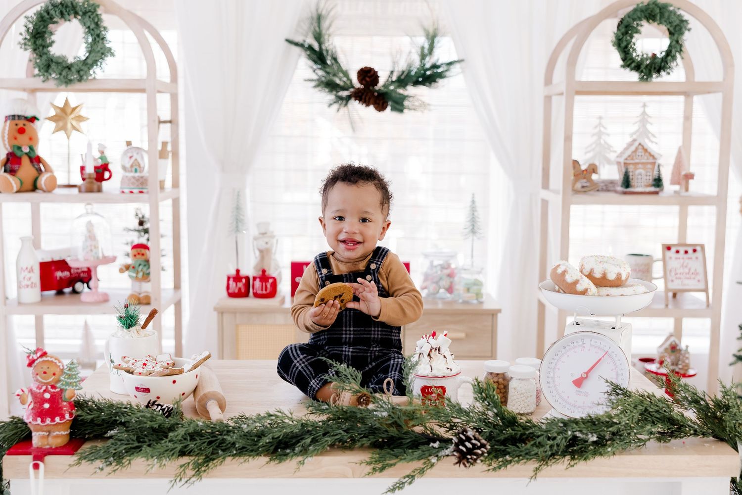 Holiday scene with small figure sitting on decorated white shelf with Christmas ornaments.