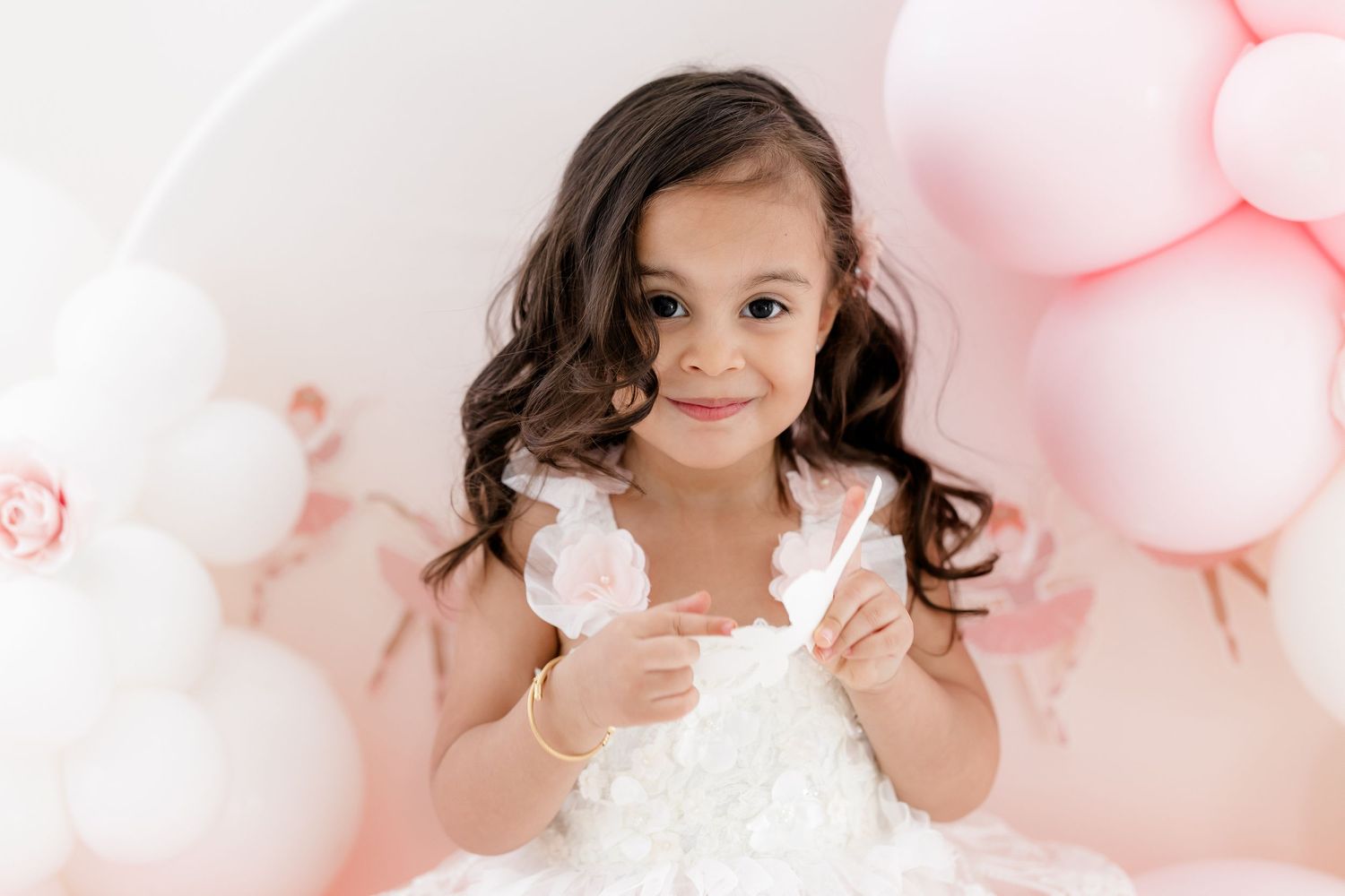 Dreamy pink balloon backdrop with white flowers creates a soft and ethereal photography setup.