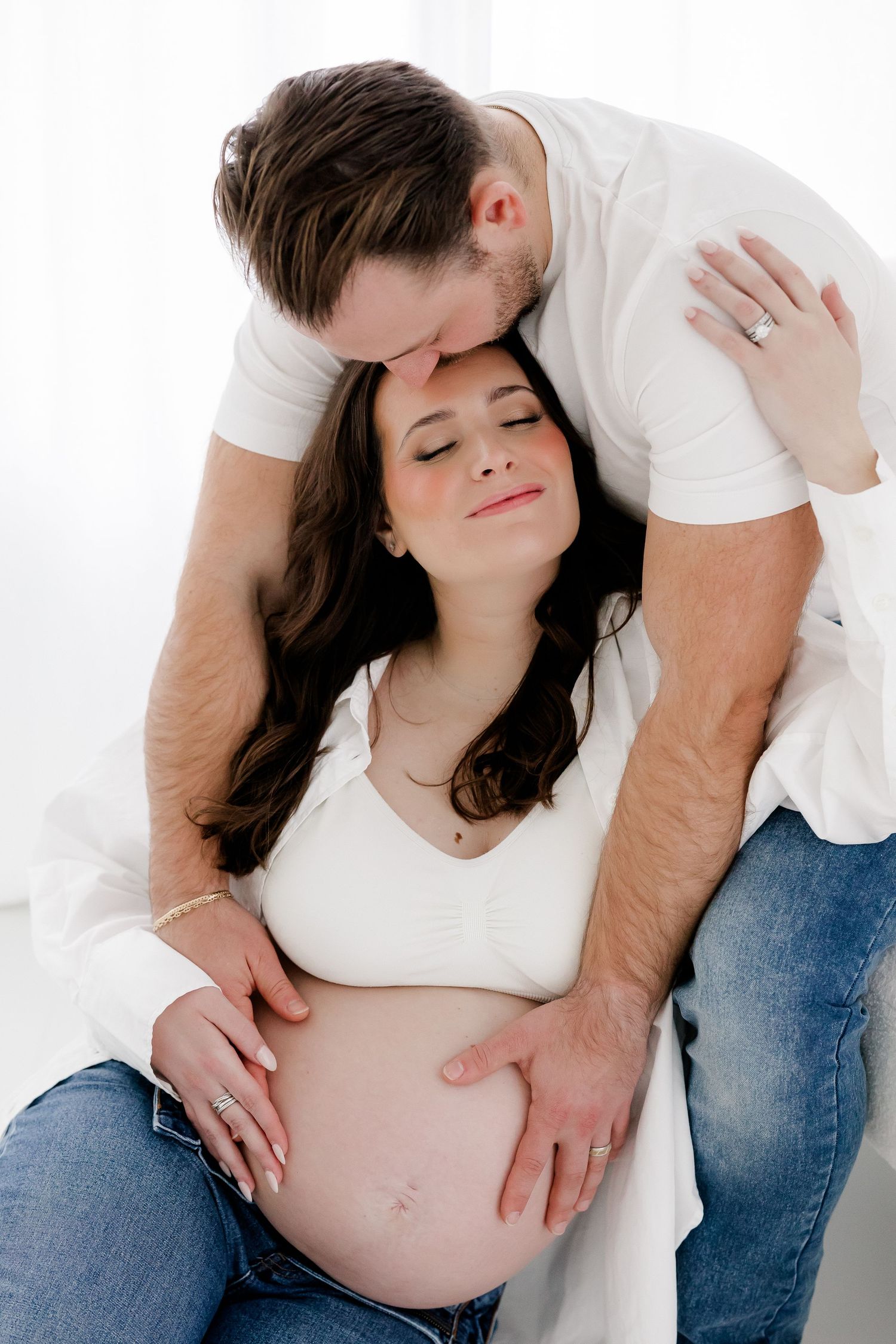 Intimate maternity photo series showing tender moments between expectant parents against white background.