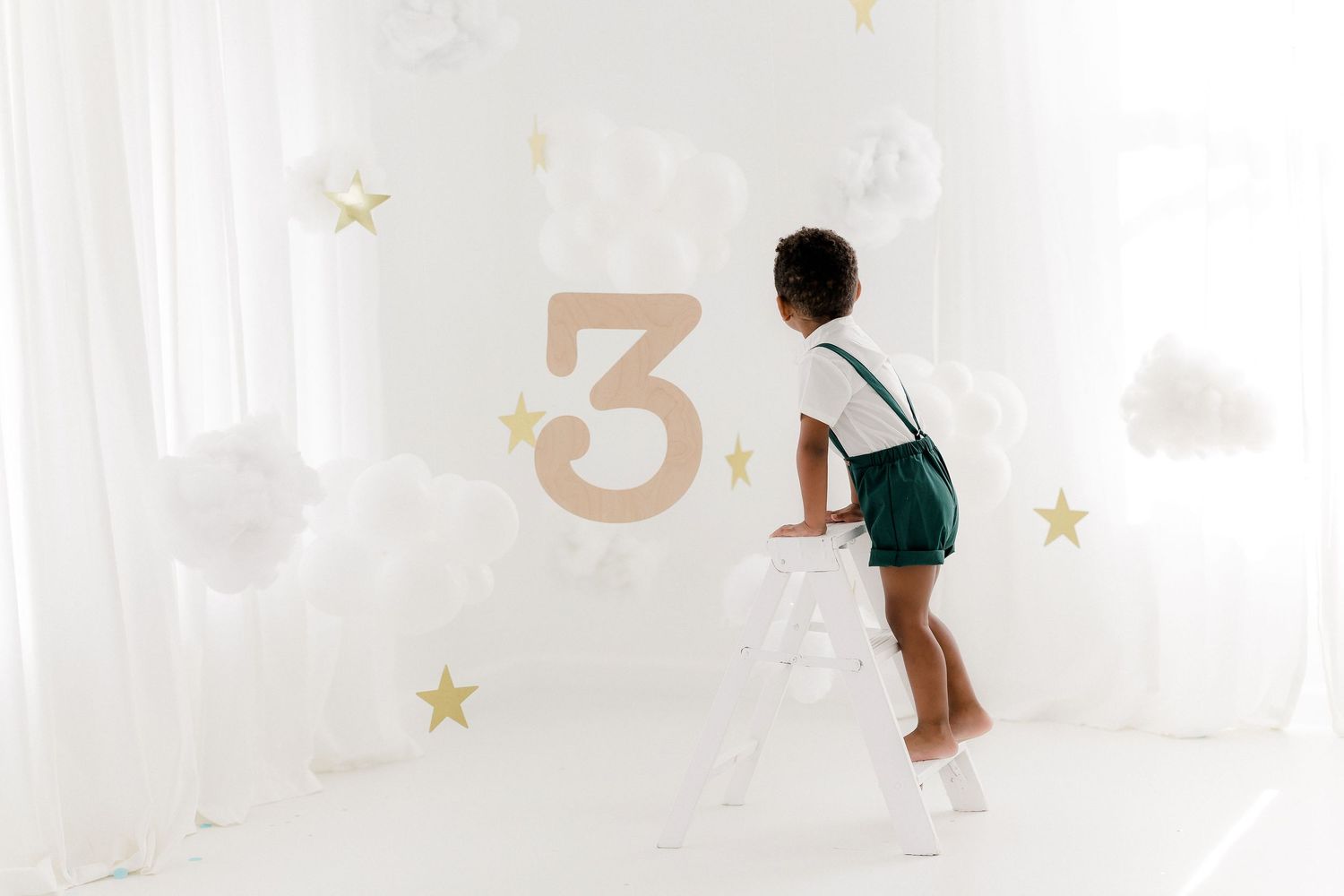 A child plays on a wall-mounted number decal in a bright white room with decorative stars.