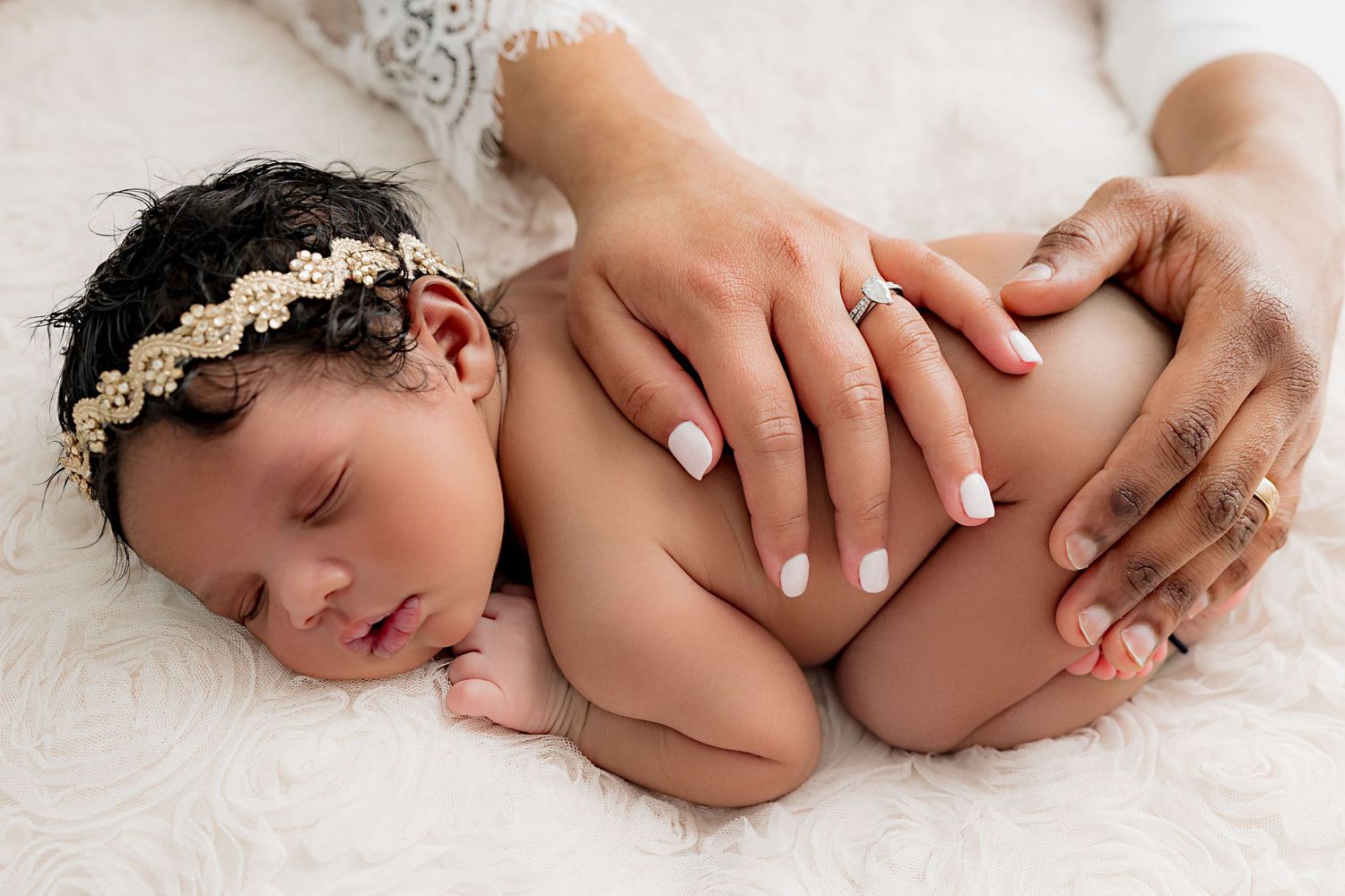 A series of tender black and white photographs showing close-up details of a sleeping newborn baby on soft white fabric.