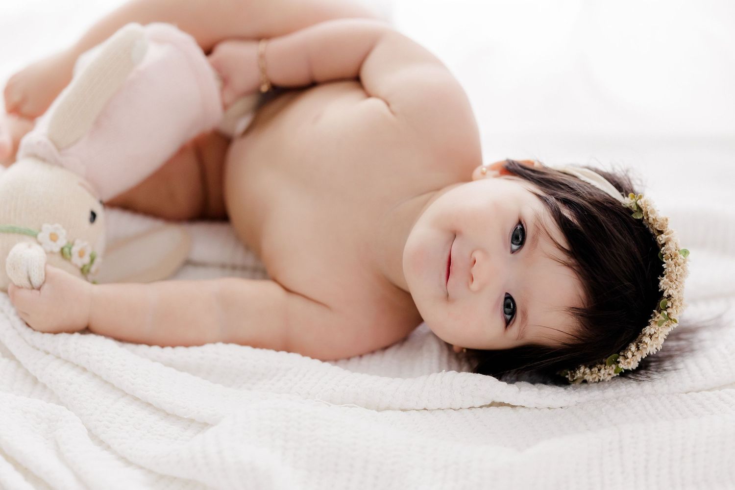A series of intimate boudoir photographs showing a person posing gracefully against white bedding and soft lighting.