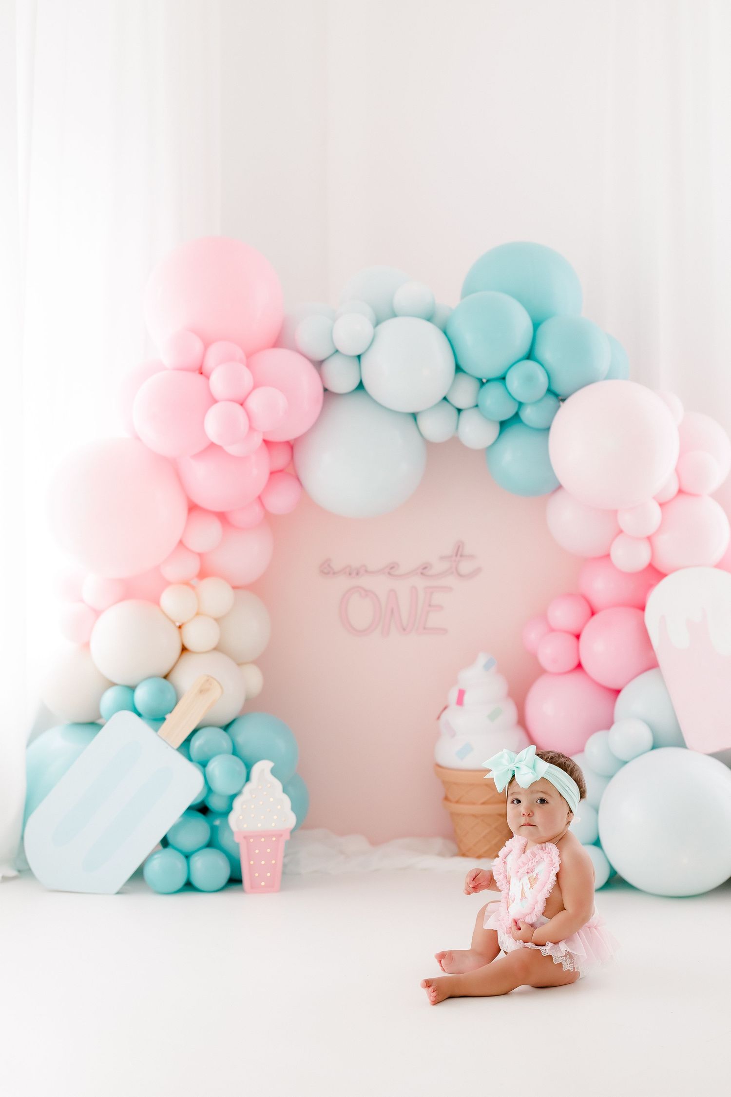 Pastel pink and blue balloon arch decorations against a light pink wall create a dreamy backdrop for a celebration.