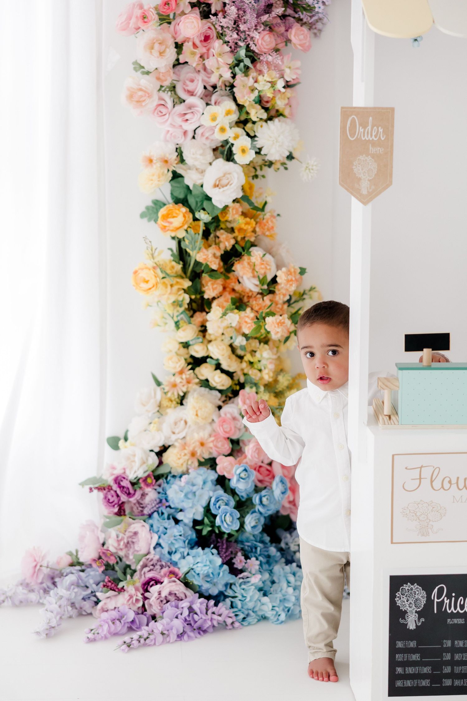 Beautiful floral backdrop with cascading pastel flowers in pink, purple, blue and yellow creates an elegant photo setting.