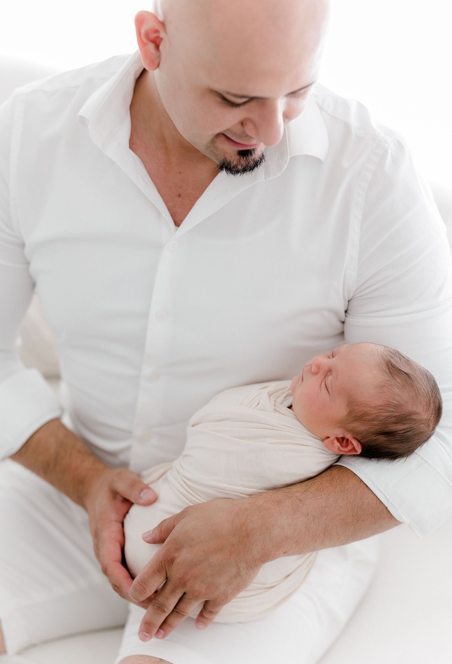 A tender moment between parent and newborn baby shown in a series of gentle white-toned photographs.