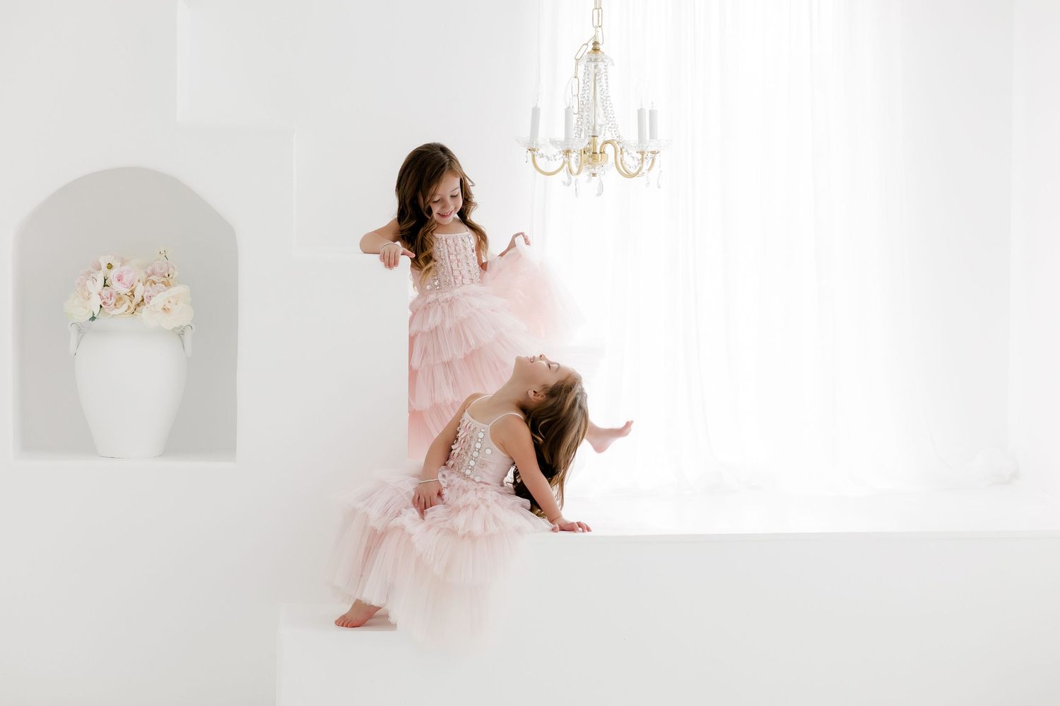 A dreamy portrait session in a bright white studio with romantic pink and gold accents and a chandelier.