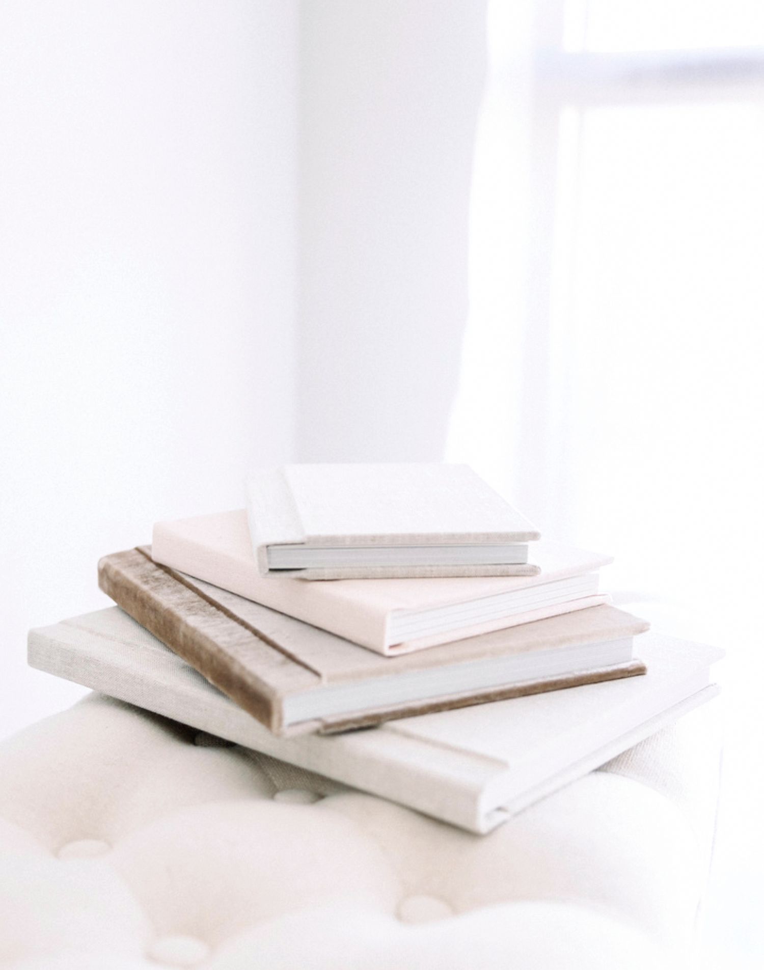 White hardcover books stacked at varying angles on a clean white surface create a minimalist composition.