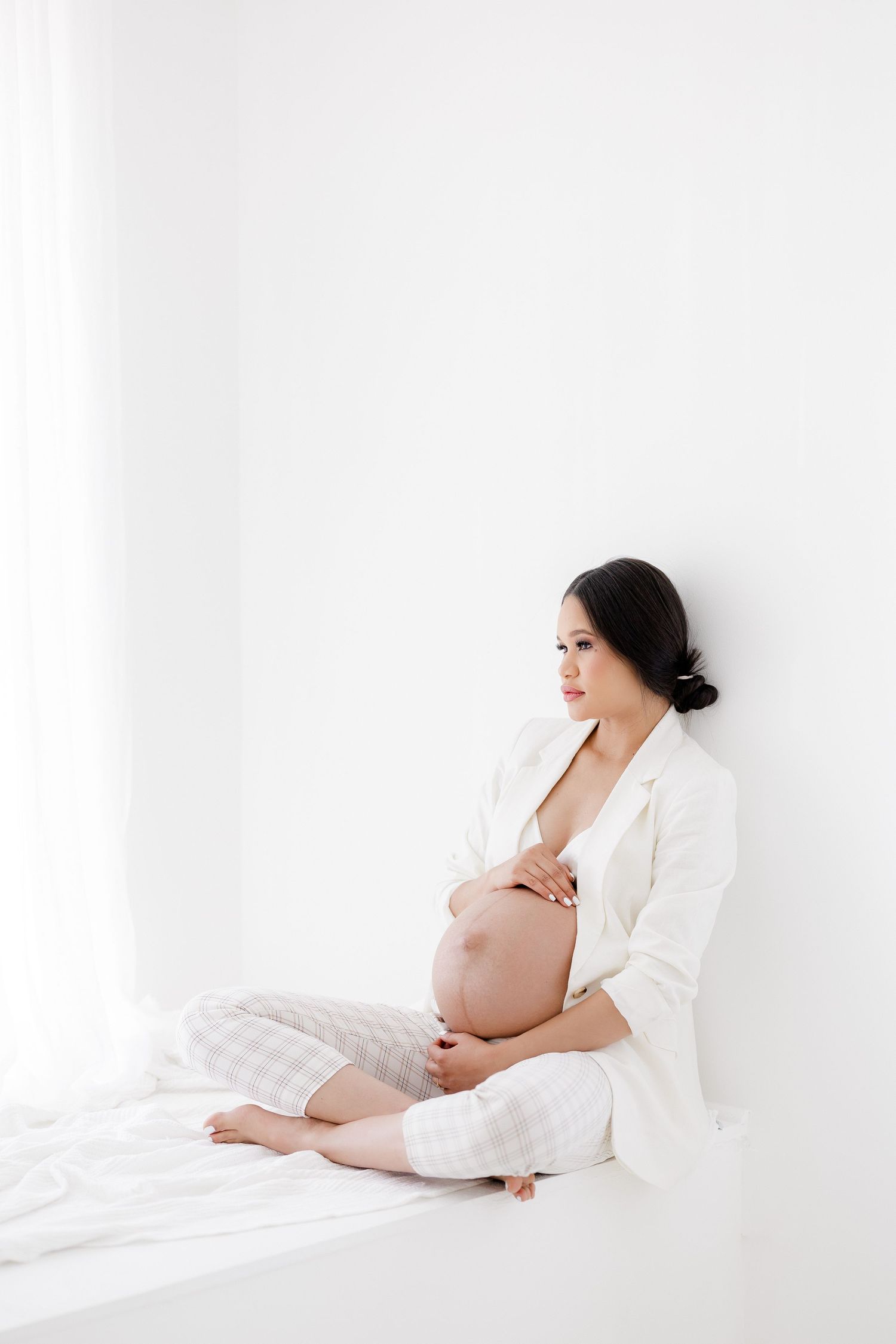 Serene maternity portraits showcasing pregnancy glow in bright white studio setting.