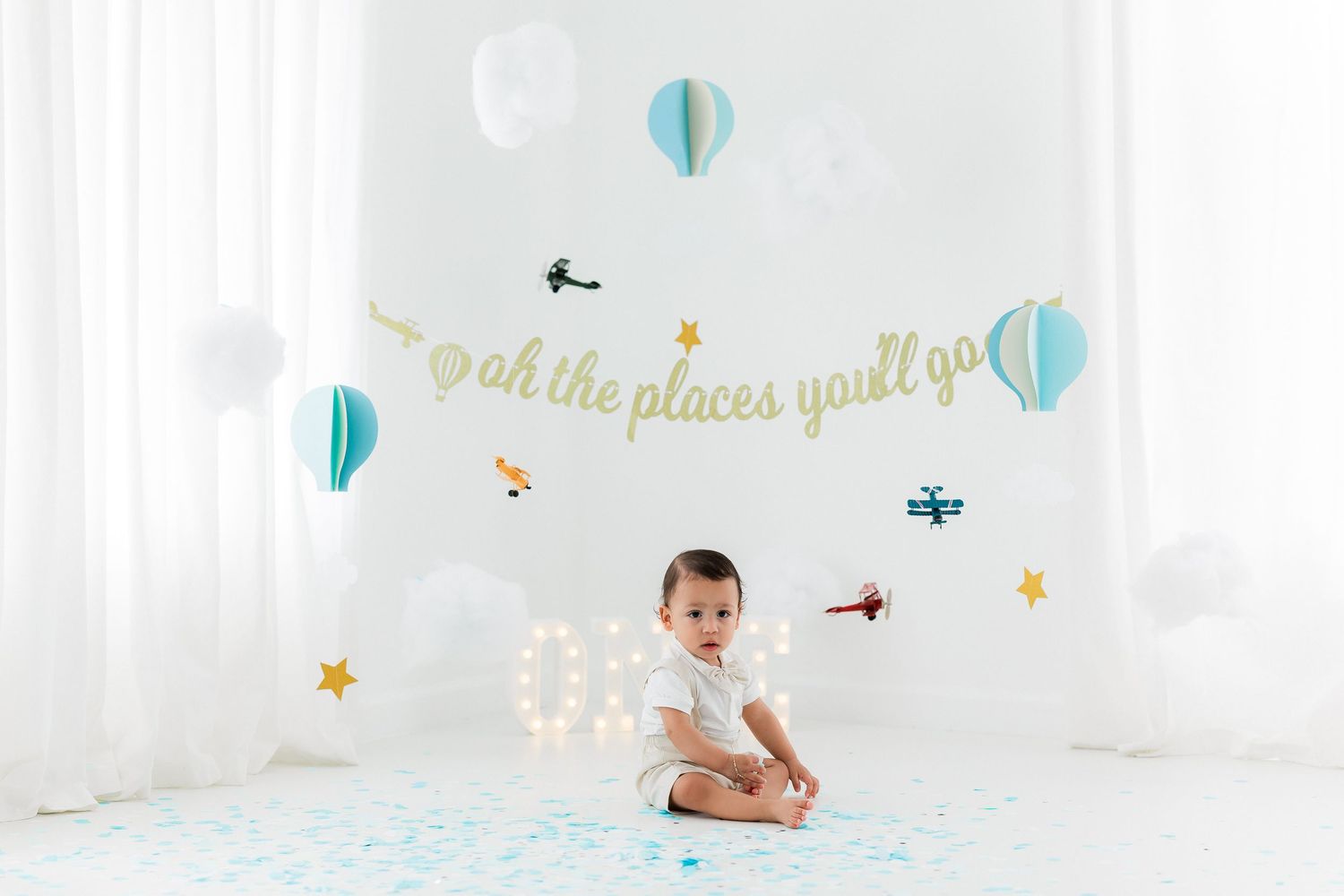 Nursery scene with 'oh the places you'll go' text, turquoise hot air balloons, and stars against white backdrop.