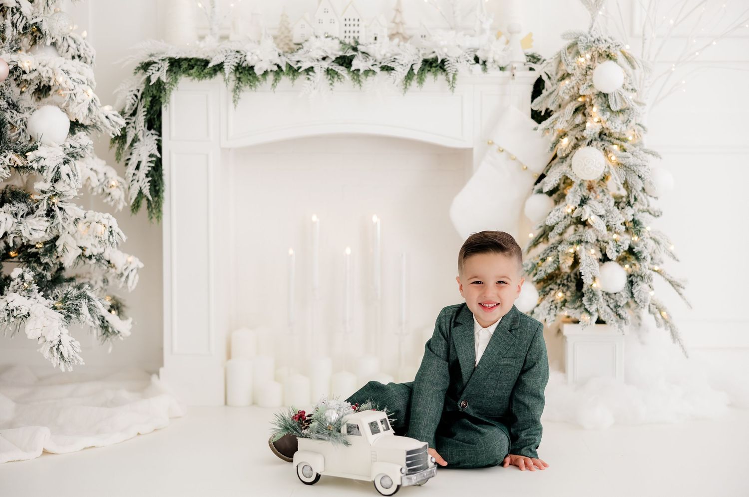 Modern Christmas studio setup with white decorations and green accents near flocked trees.