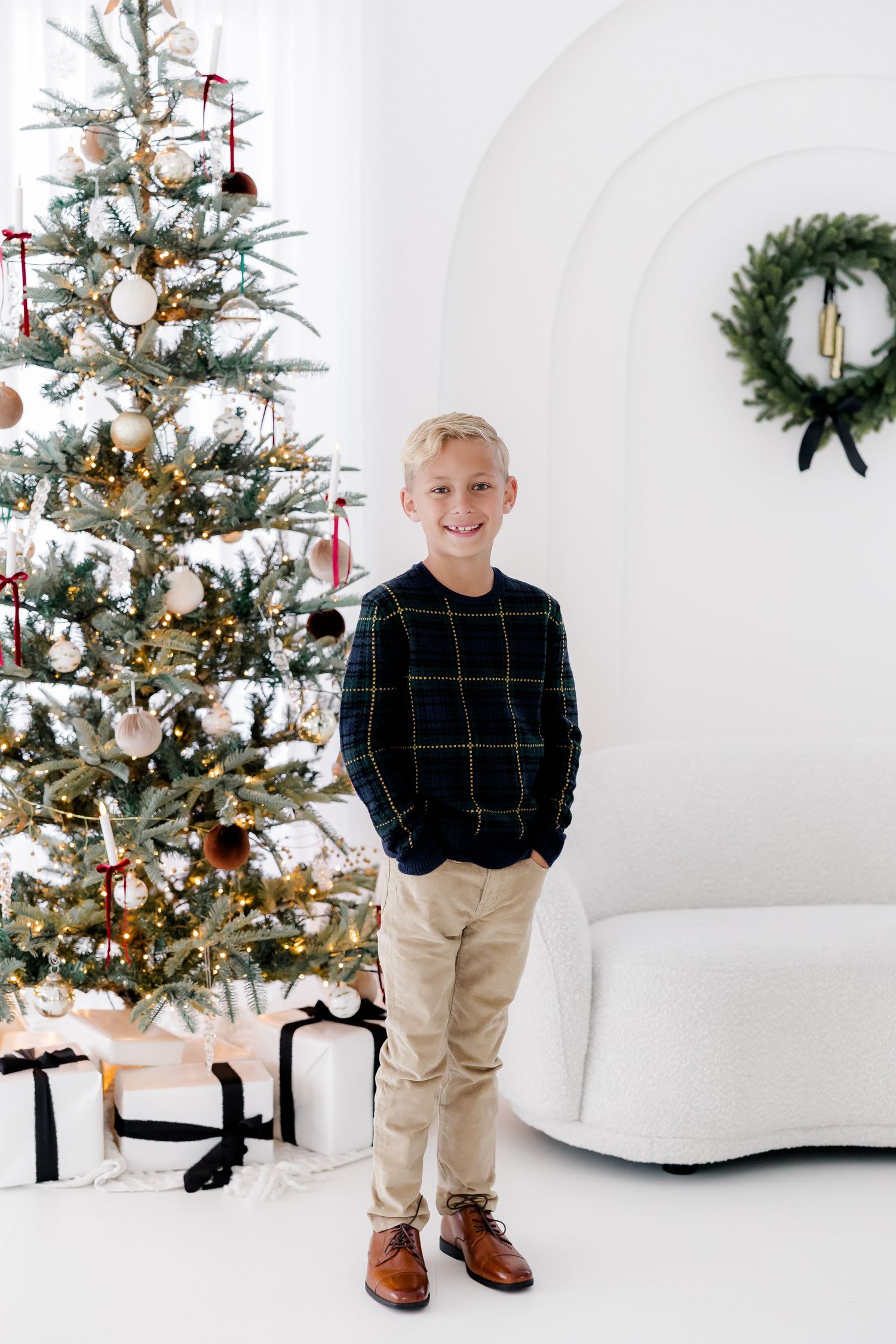 Holiday portrait setup with decorated Christmas tree and white modern furniture.