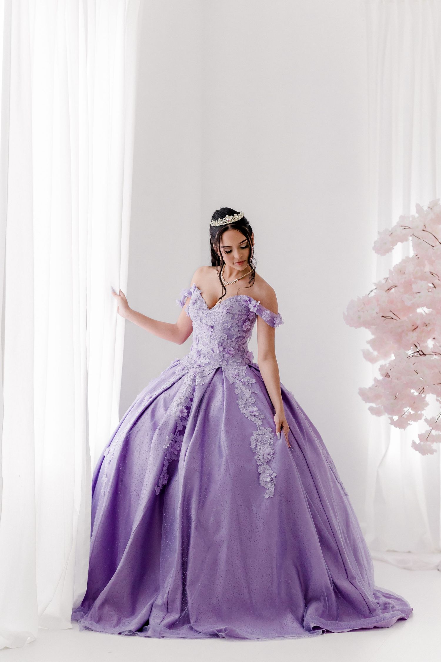 A lavender ball gown with floral appliques shown from multiple angles in a white studio setting.