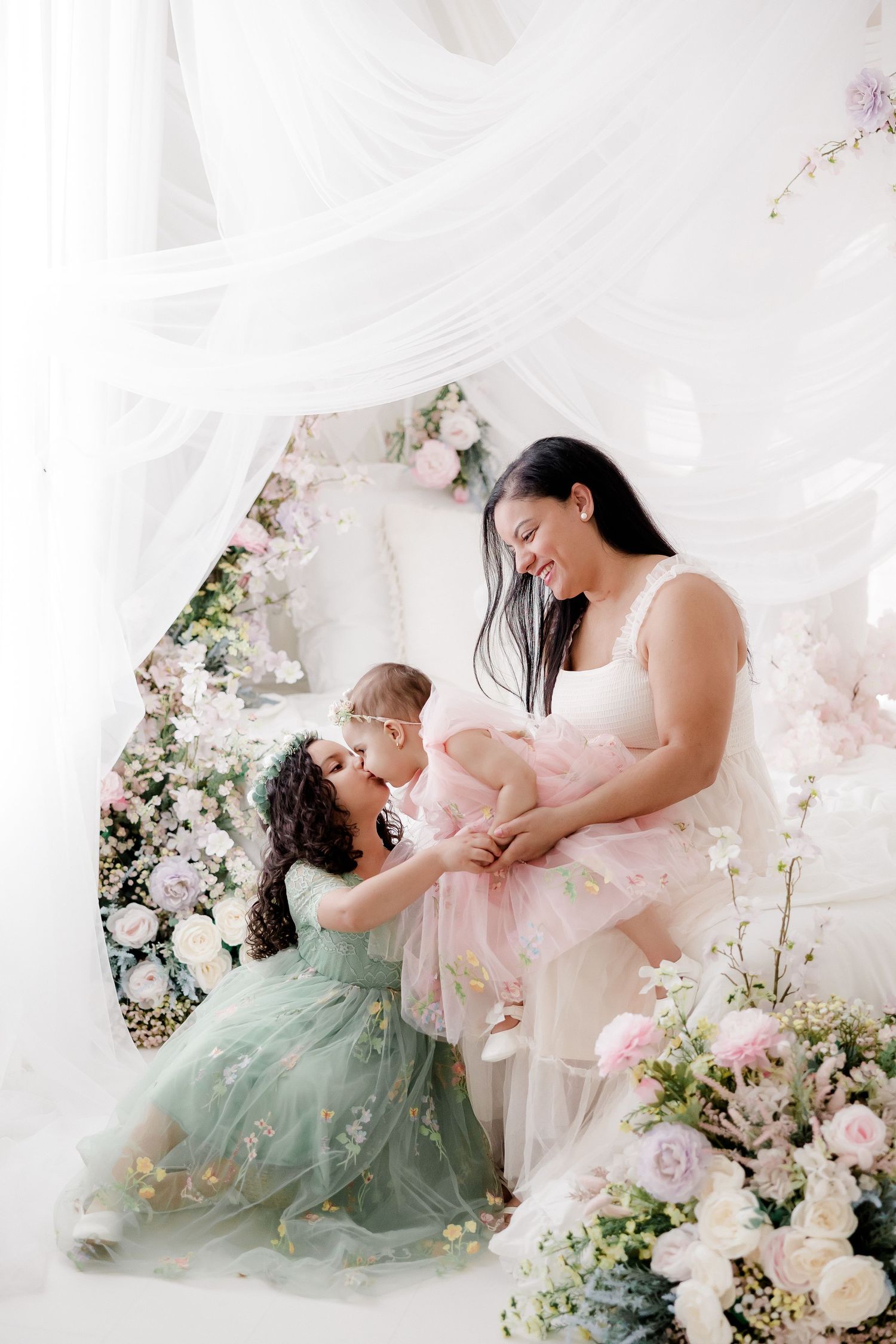 A dreamy mother and daughter photoshoot featuring soft pink and mint green dresses surrounded by delicate floral arrangements.