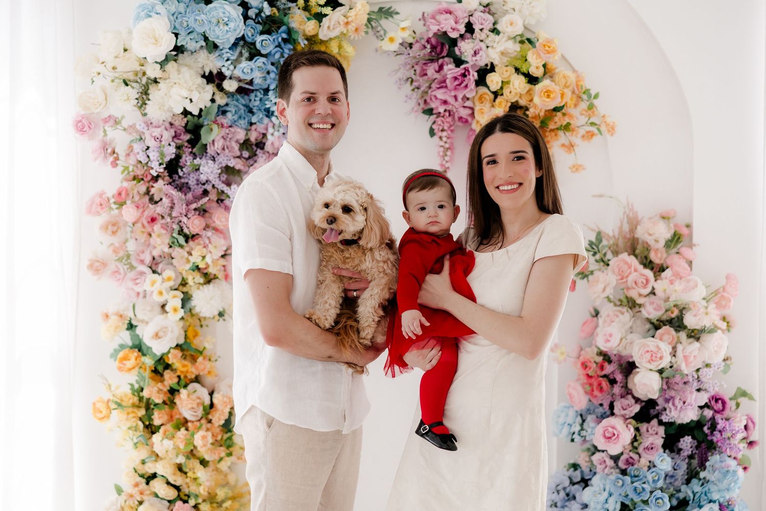 A colorful floral backdrop adorns a studio photo session featuring warm smiles and festive holiday attire.