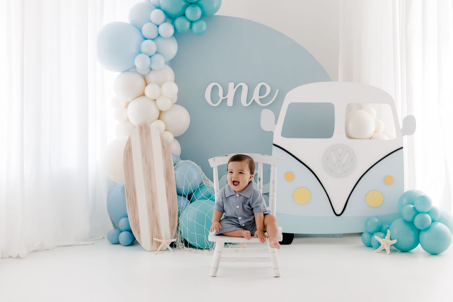 Baby's first birthday party setup with blue and white balloon decorations and a vintage camper theme.