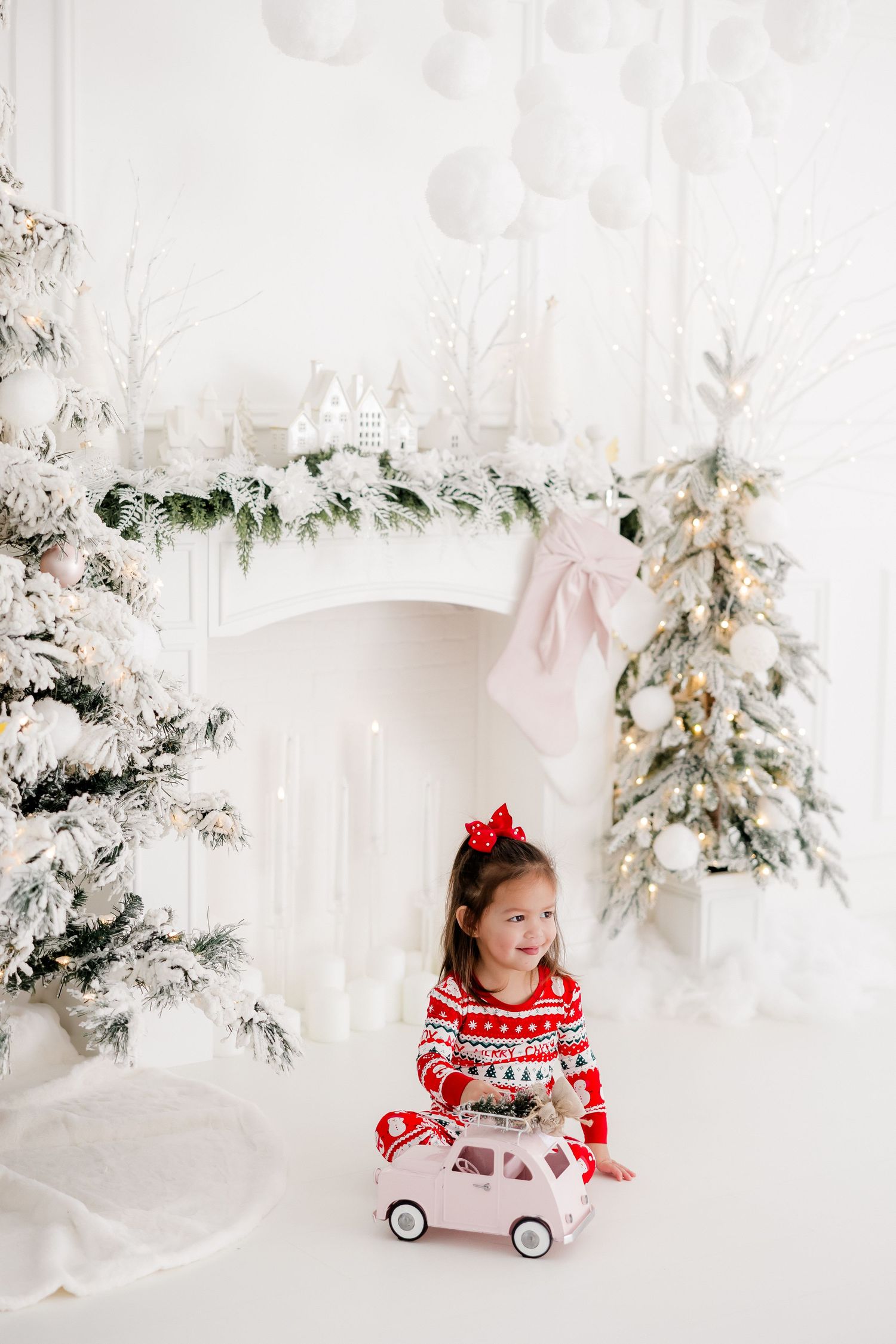 Winter wonderland photo session with flocked trees and red holiday decor.