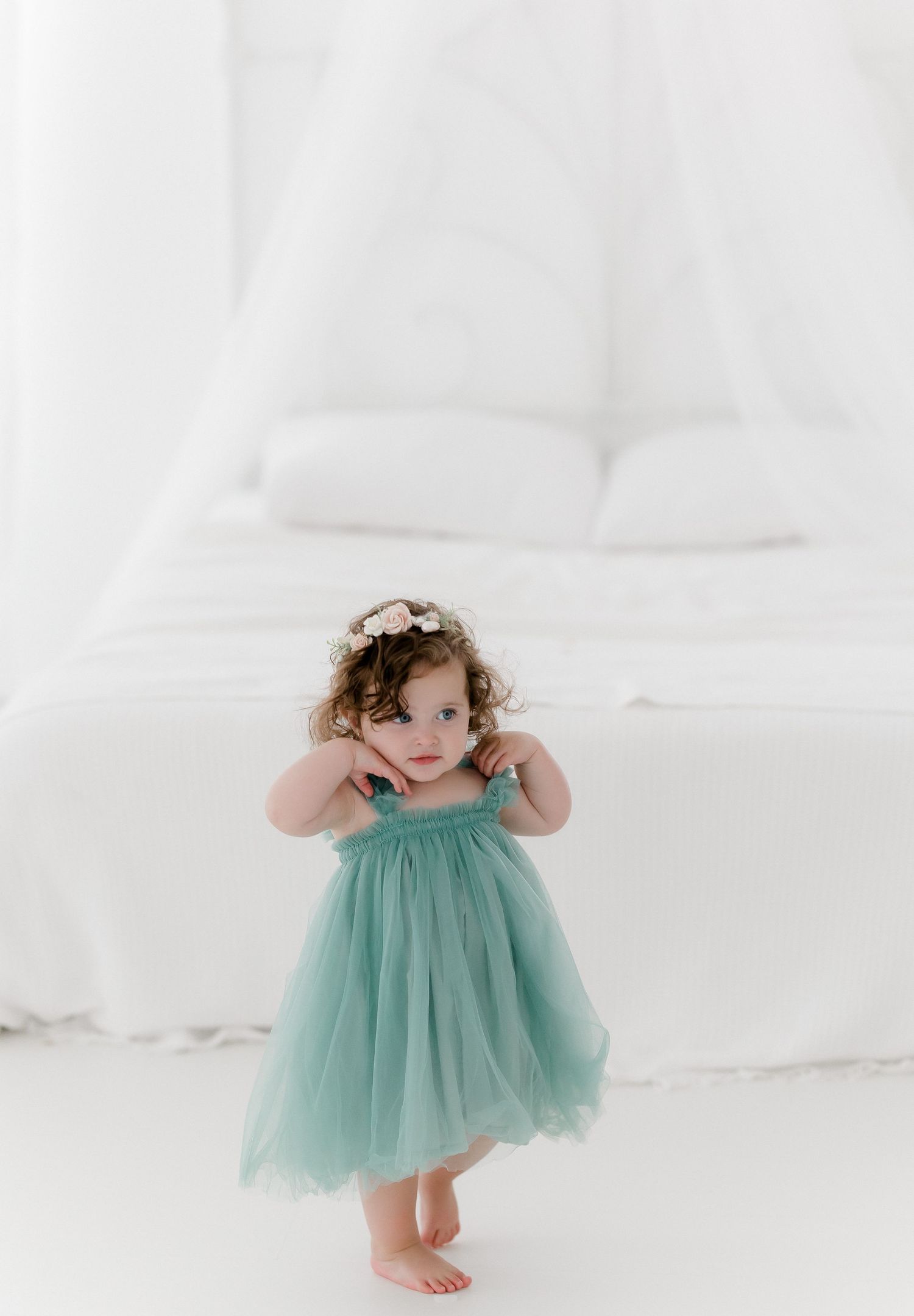 Ethereal studio portrait featuring mint green tulle dress against pure white background.