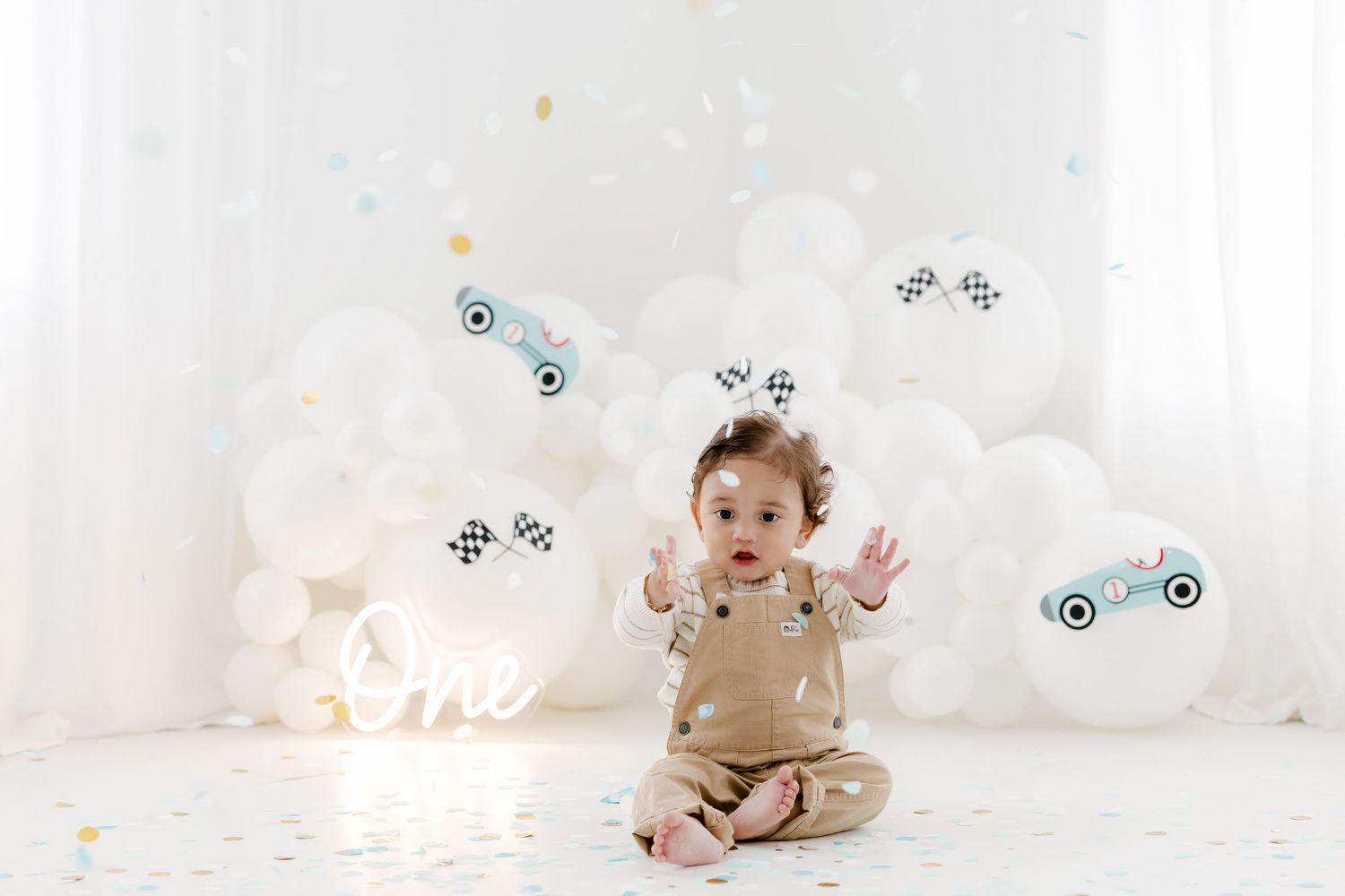 Baby sitting in soft white studio setting with floating bubbles and ethereal lighting around them.
