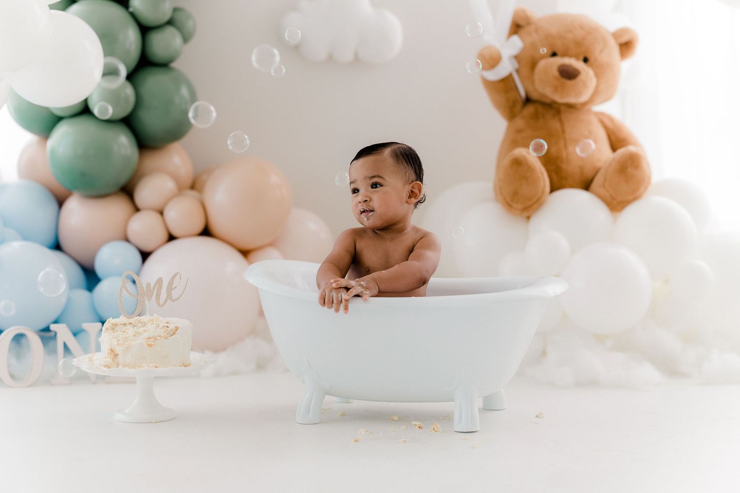 Bath time photo session with teddy bears and balloon decorations.