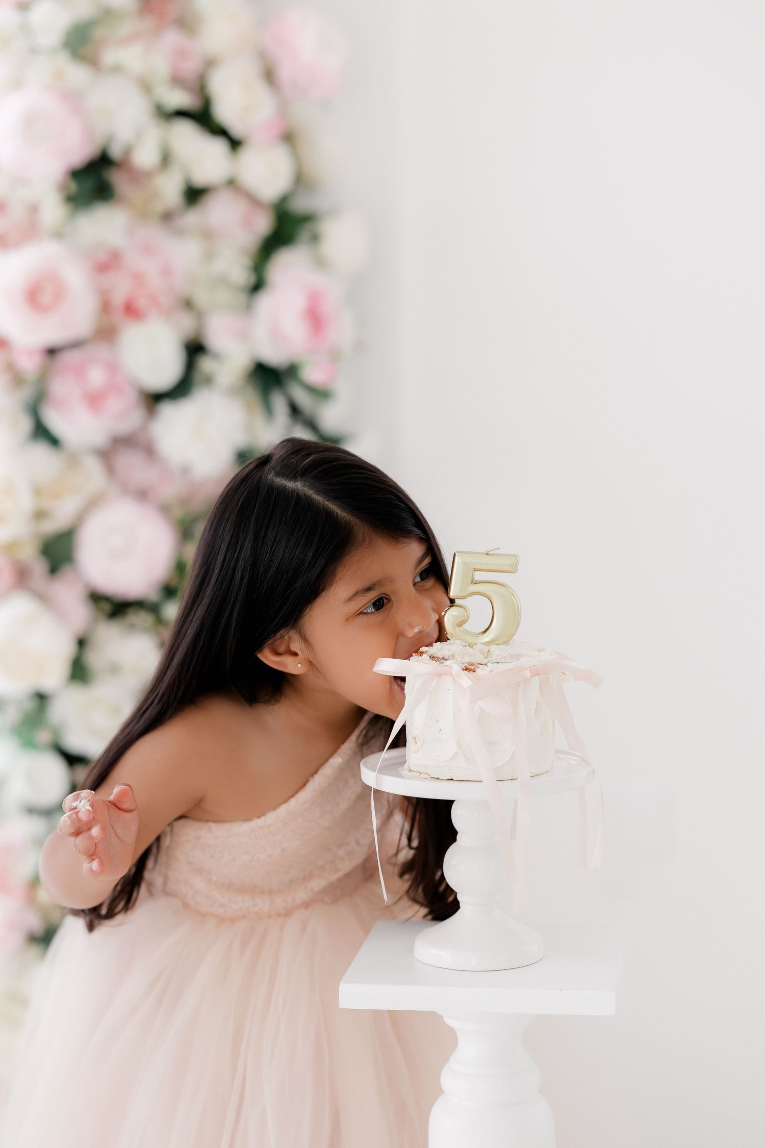 A playful sequence of someone pretending to bite a small white cake against a floral backdrop.