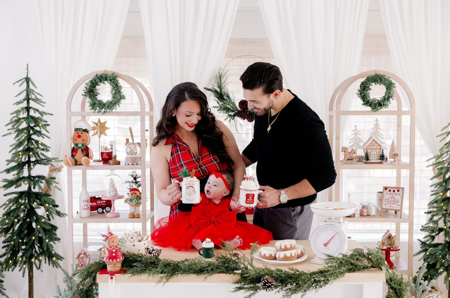Festive Christmas photo session in an all-white room with wreaths, trees and holiday decor.