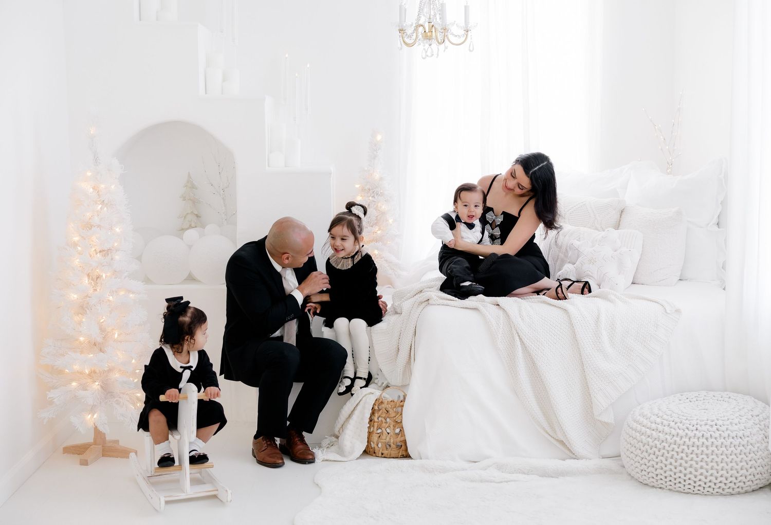 Family enjoys playful moments in white holiday photo studio setting.